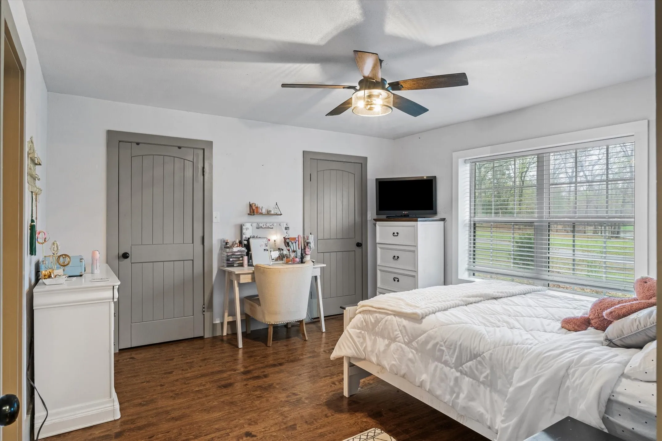 Bedroom with multiple closets, dark wood-style flooring, and a ceiling fan