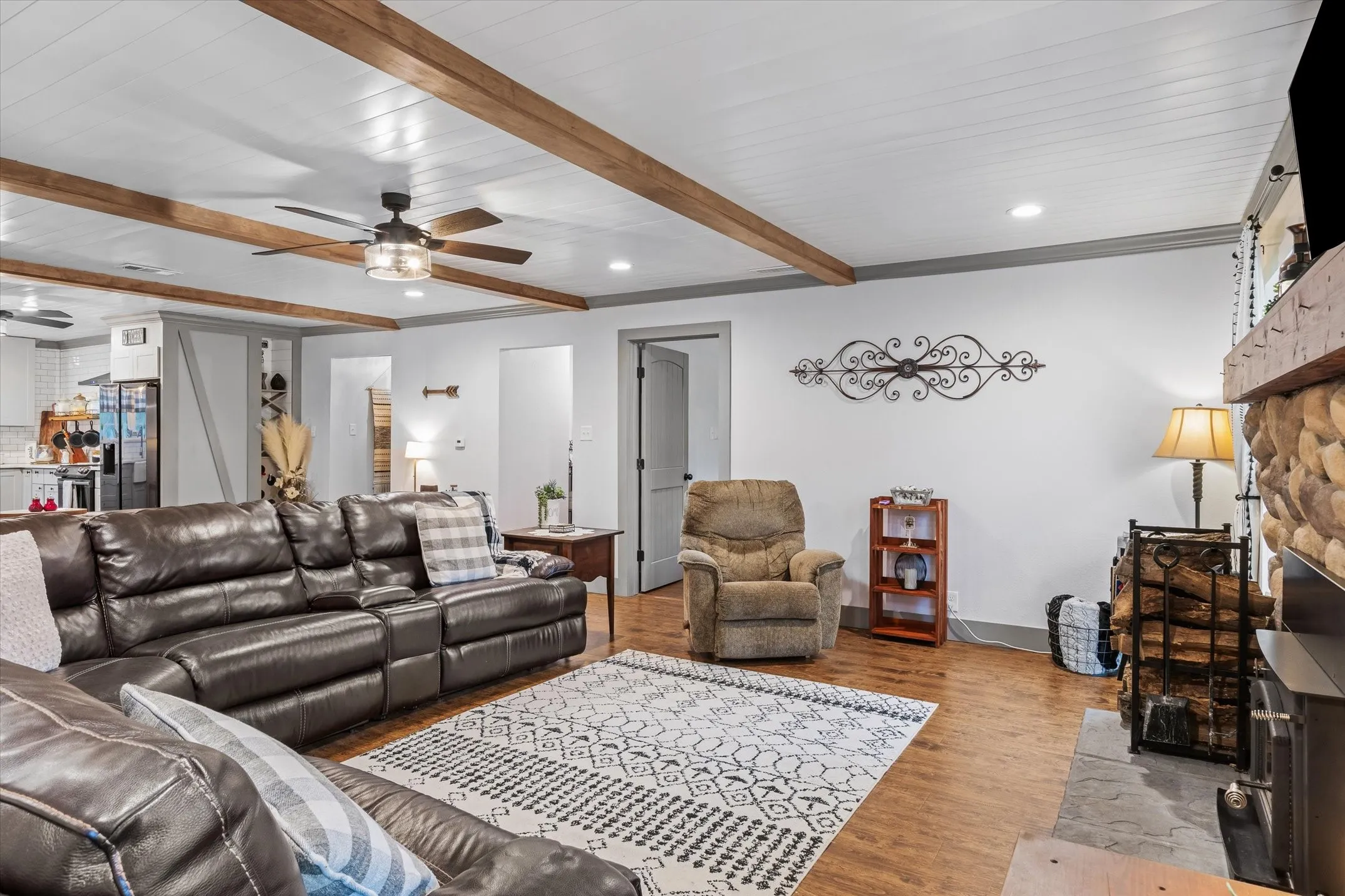 Living room with a ceiling fan, a fireplace, wood finished floors, recessed lighting, and beam ceiling
