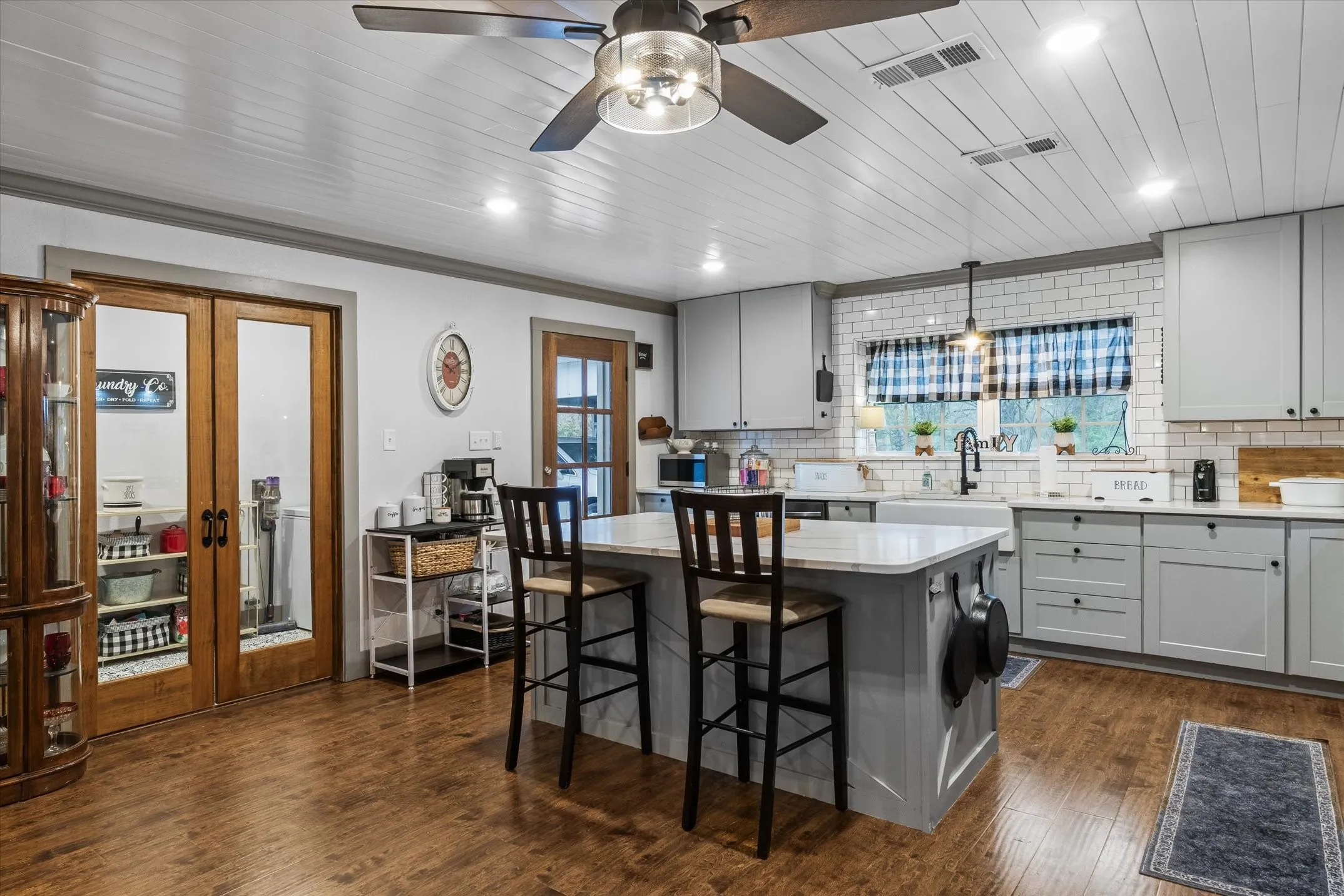 Kitchen featuring gray cabinetry, a center island, backsplash, and french doors to the laundry room
