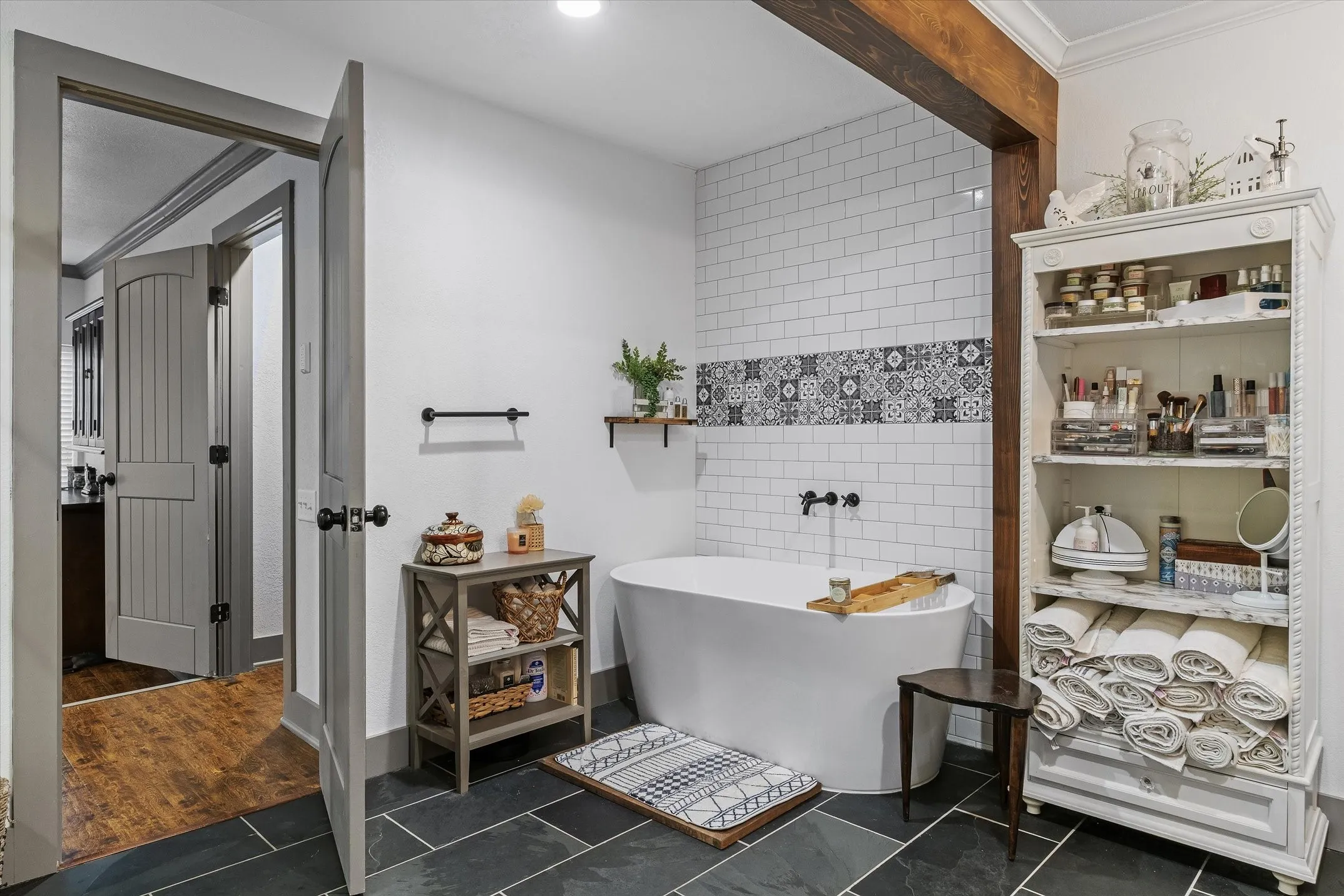 Bathroom featuring tile walls, dark tile patterned flooring, a soaking tub, and crown molding