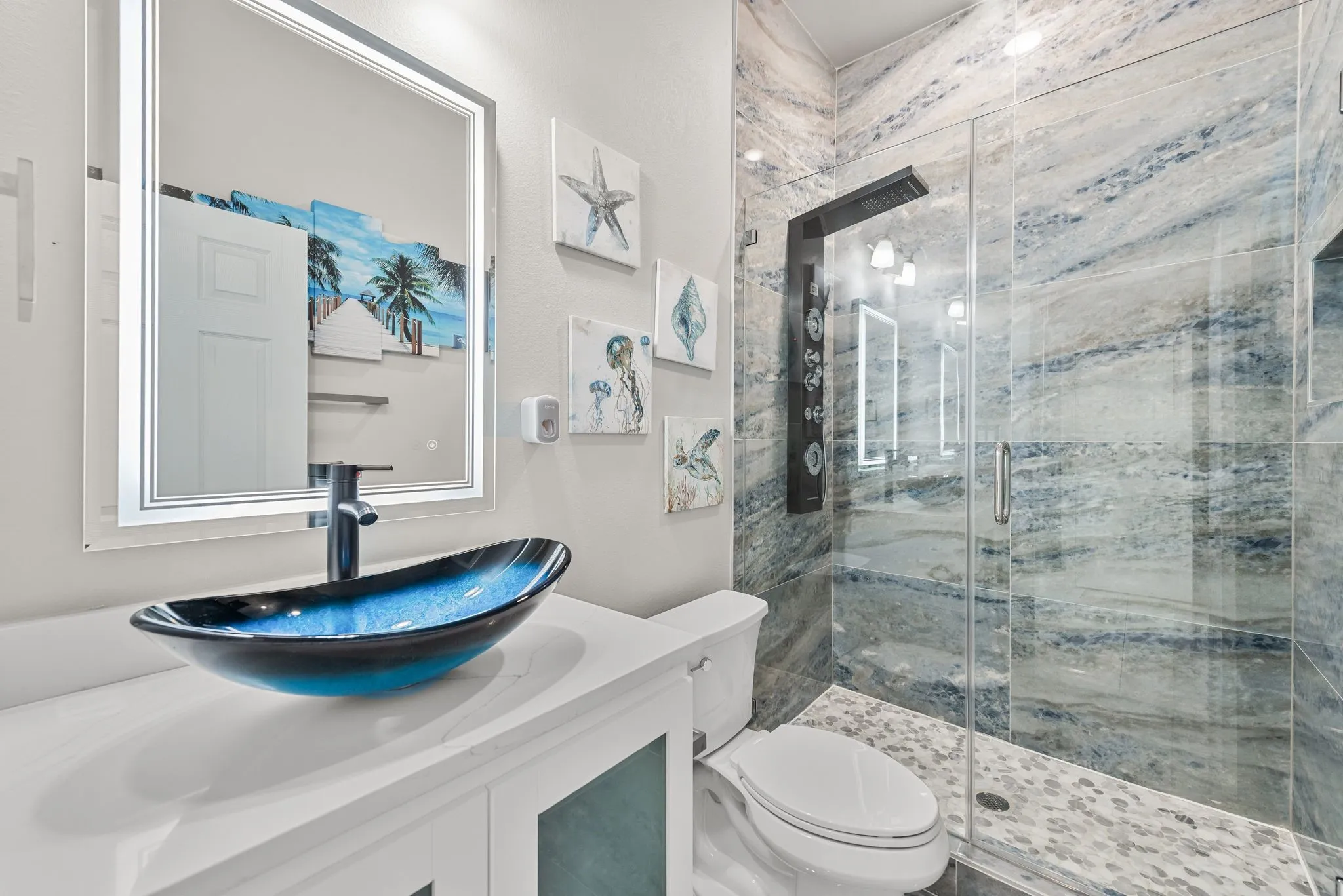 Bathroom with blue vessel sink, walk-in shower, and coastal-inspired design details.
