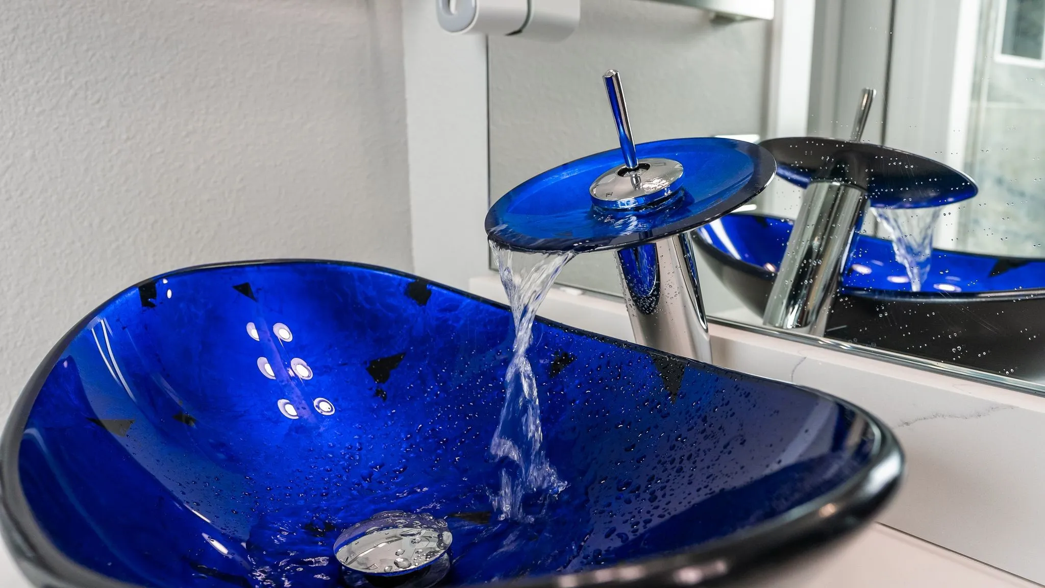 Close-up of blue glass vessel sink adding lake-inspired style to the bathroom.