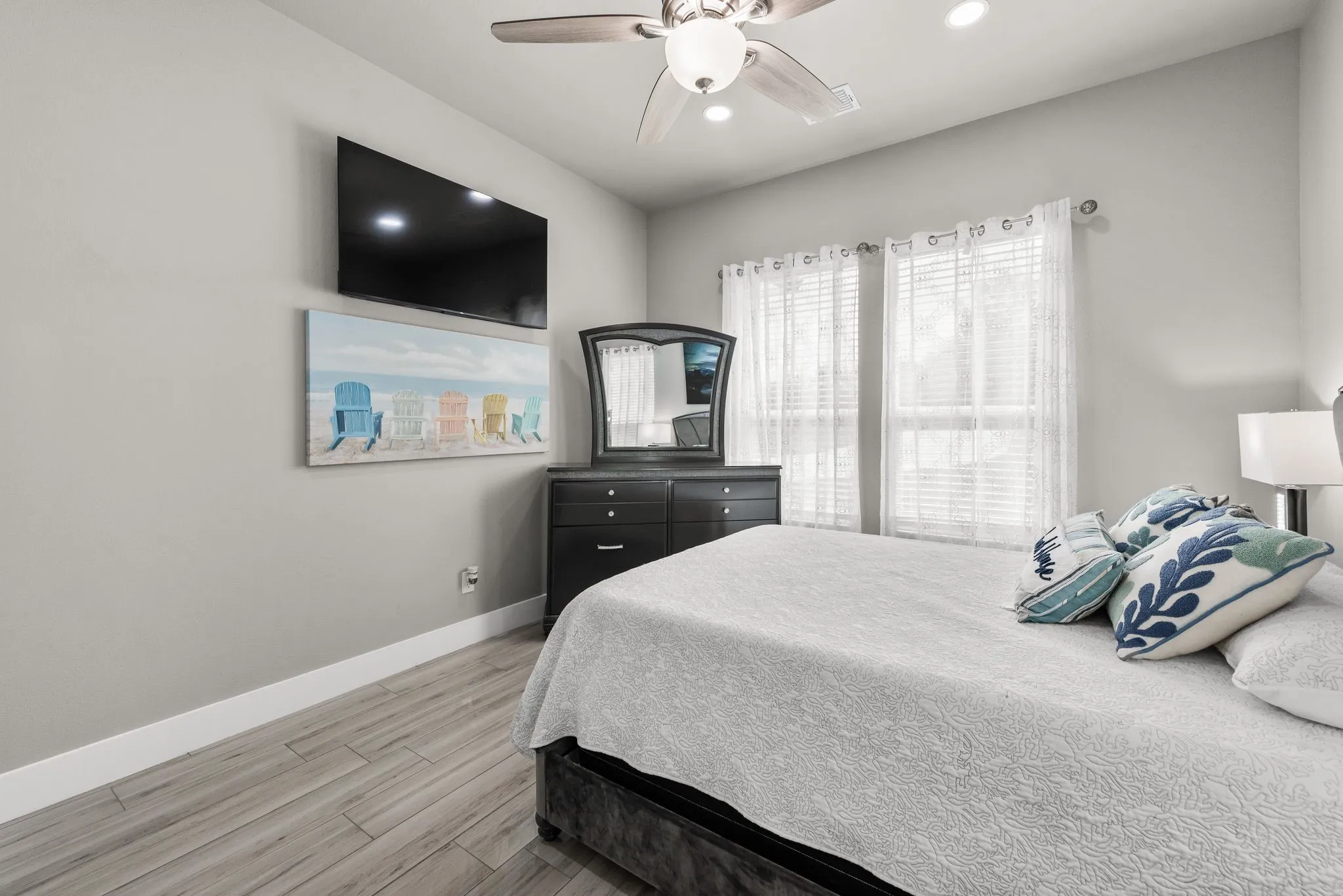 Guest bedroom with ceiling fan, TV, natural light, and comfortable lake house layout.