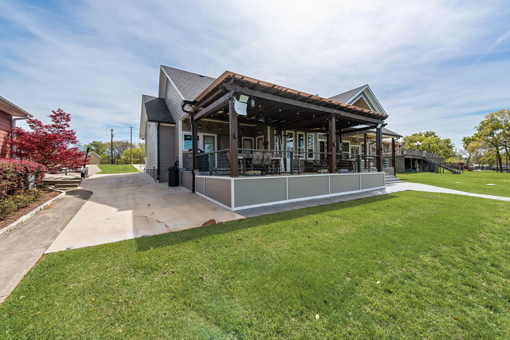 Rear exterior view with covered patio, green lawn, and easy access to the lake.