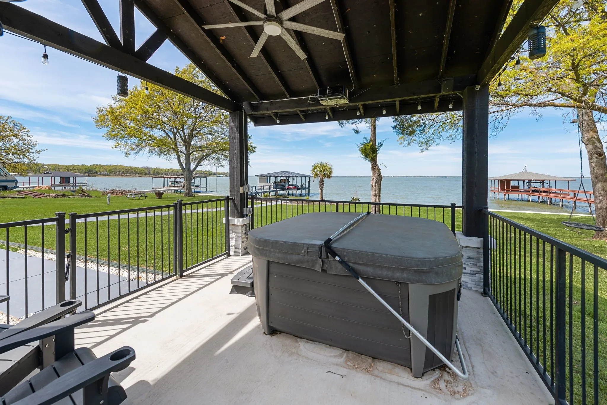 Pergola-covered hot tub area with water, electric, speakers, and lakefront relaxation potential.