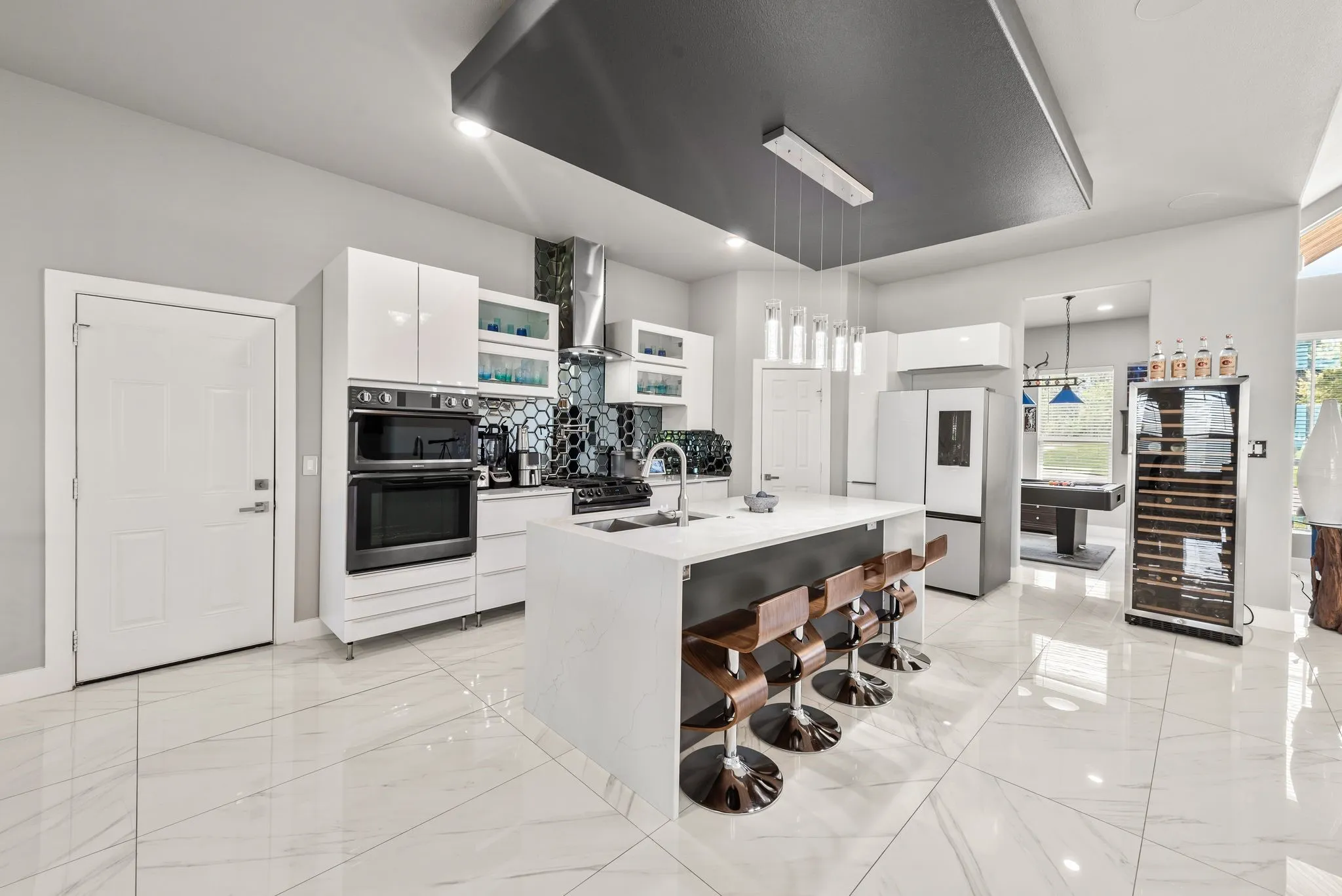 Bright kitchen with double ovens, gas range, large island, and abundant cabinetry.