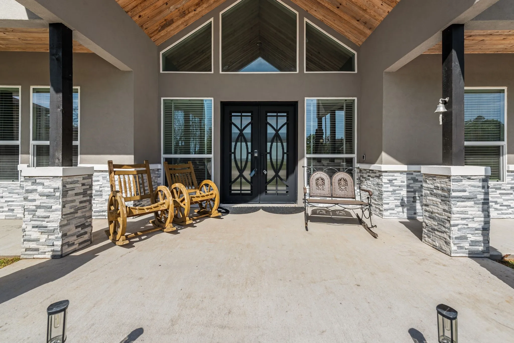 Covered front entry with Craftsman details and expansive windows at this Streetman lake house.