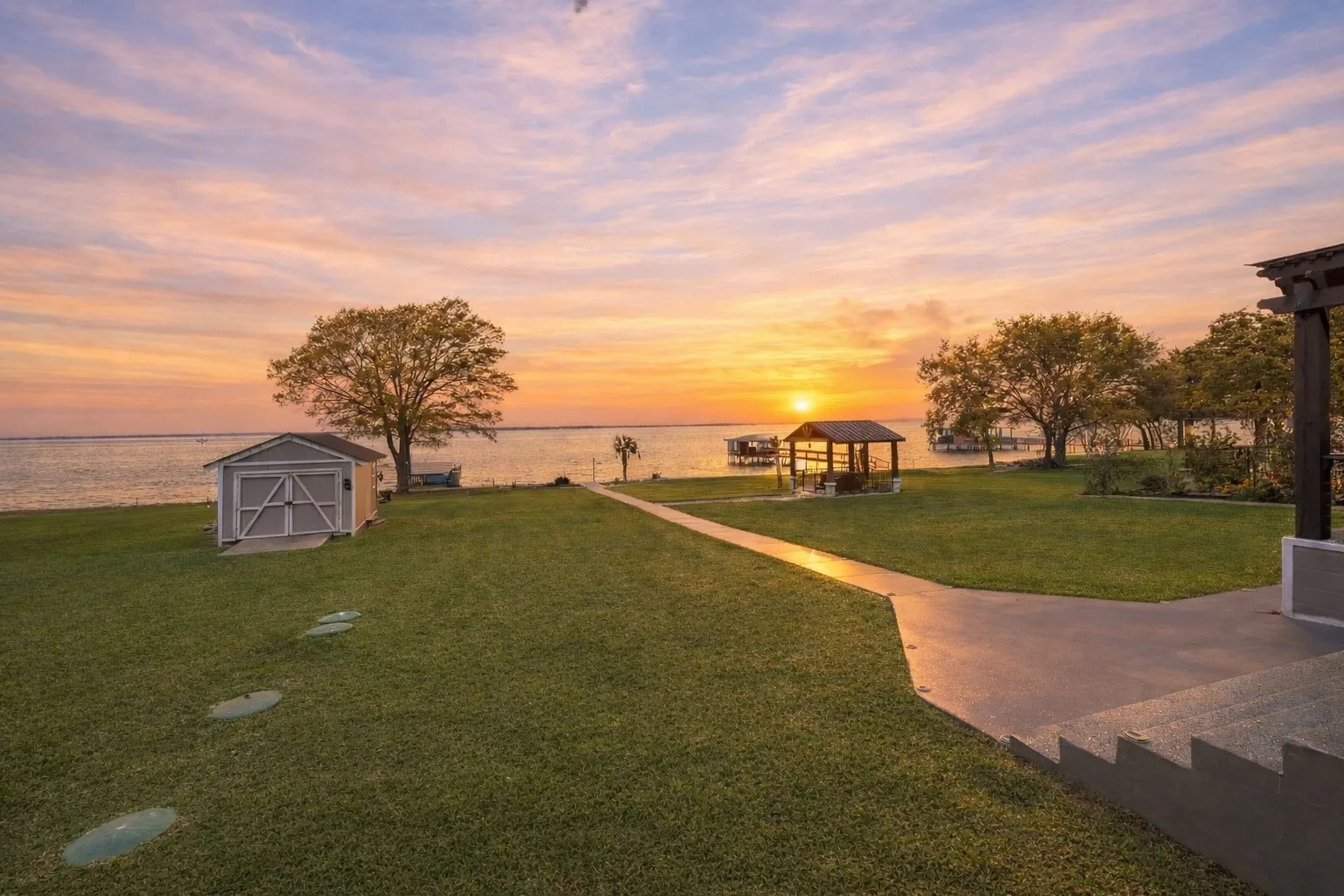 Spacious backyard near the shoreline with lake views, storage building, and outdoor living potential.
