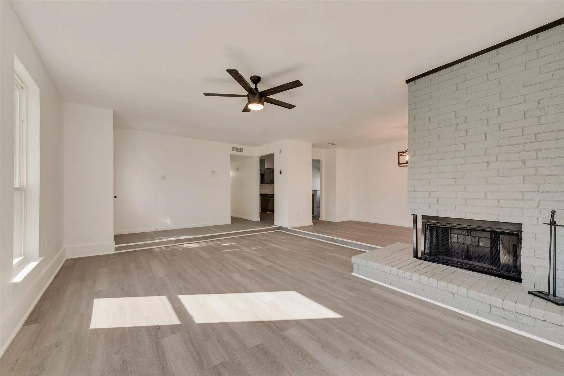 Unfurnished living room with light wood finished floors, a fireplace, and a ceiling fan