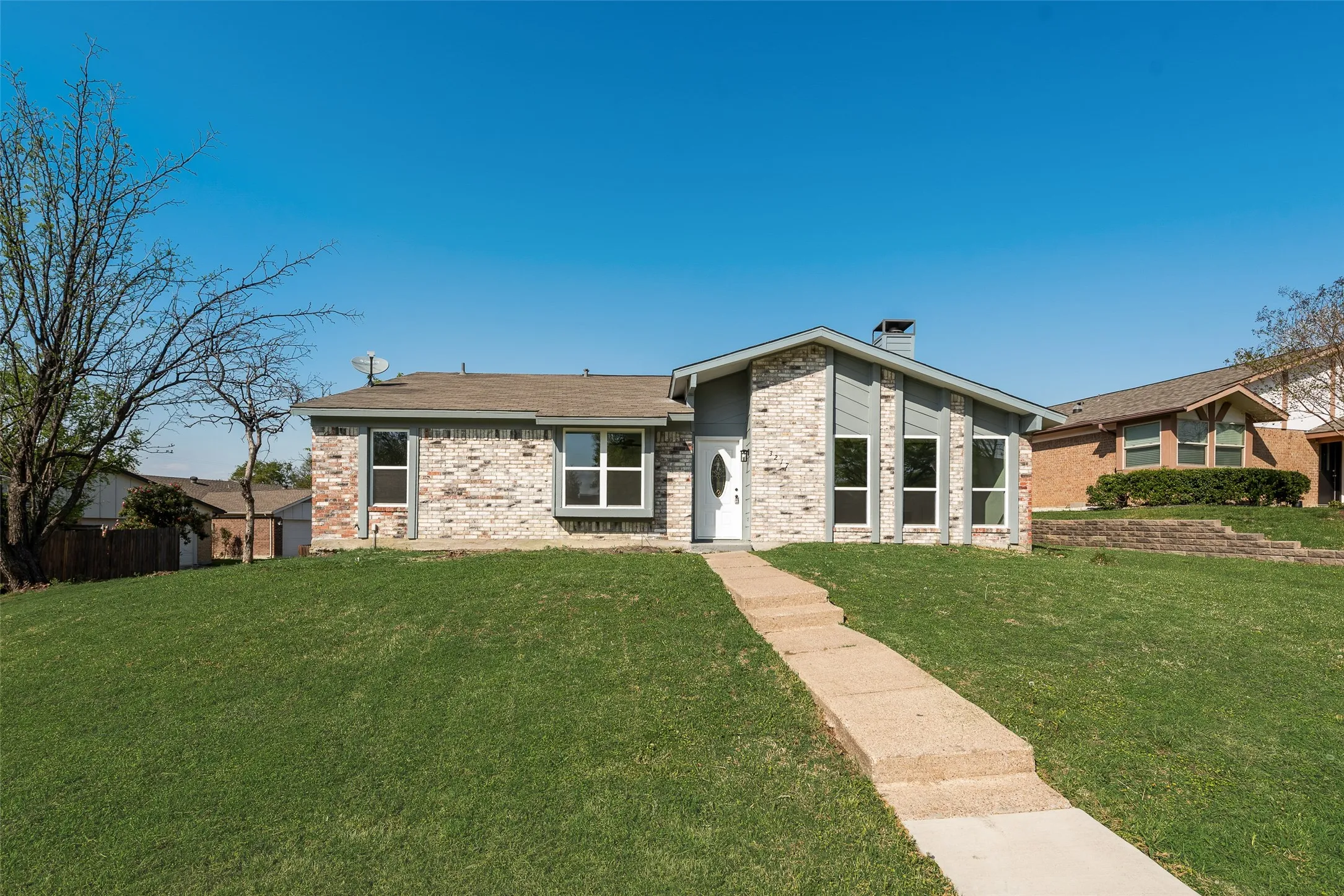 Mid-century home with brick siding, a chimney, and a front yard
