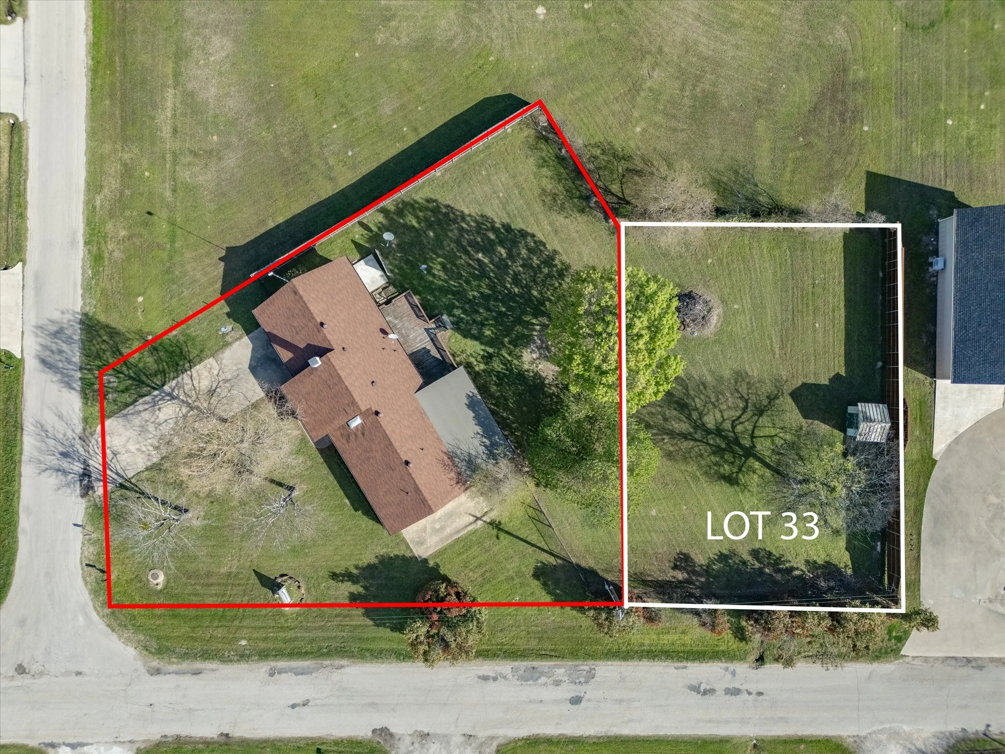 Expansive corner lot featuring a single-story residence with a brown shingle roof, a rear deck, and a detached shed
