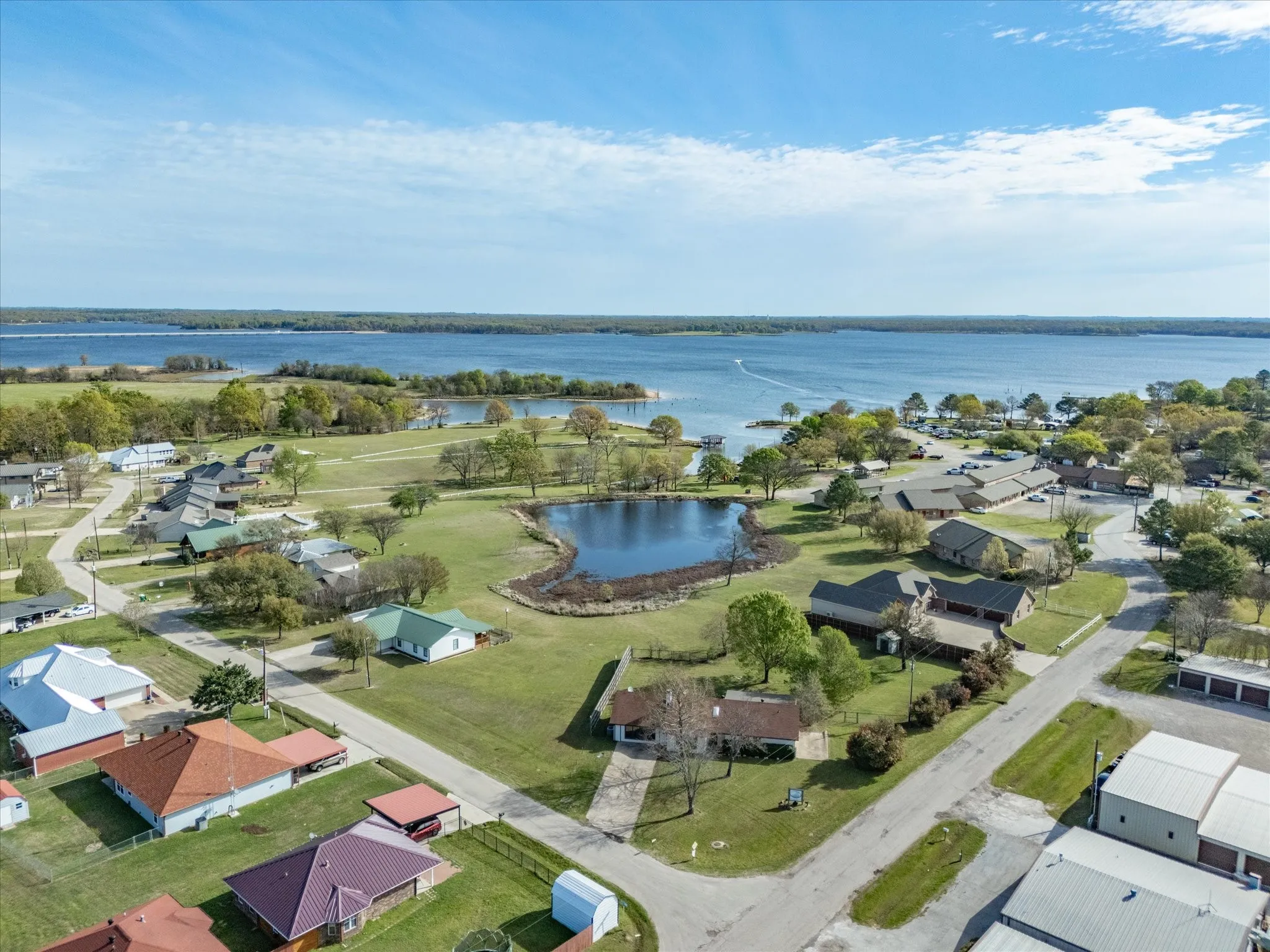 Expansive lakefront setting featuring a concrete boat ramp, a sandy shoreline, and a wooden dock extending into the water
