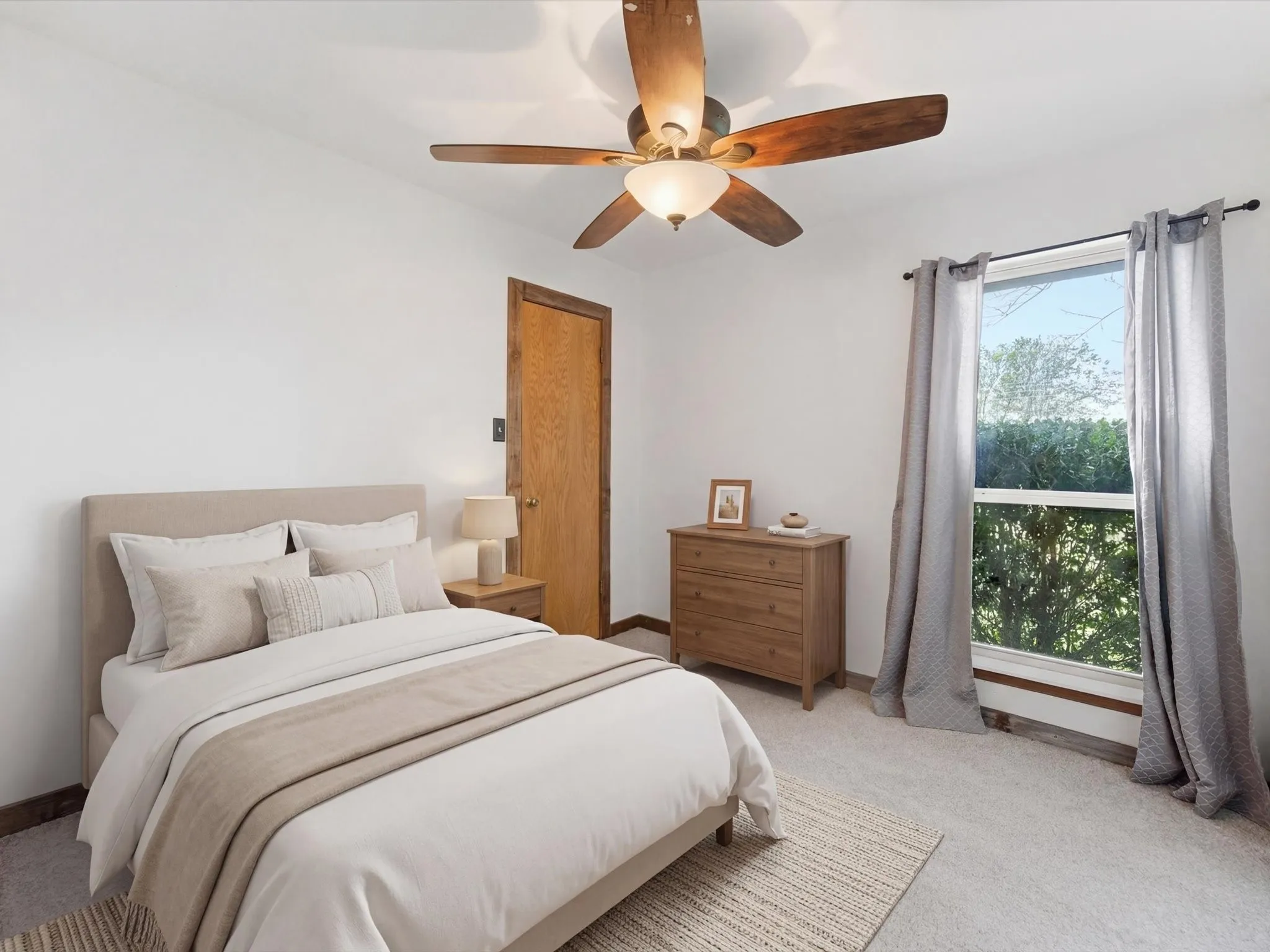 VIRTUALLY STAGED!Carpeted room featuring a ceiling fan with integrated lighting, a single window with curtain rods, and wood-finish trim around the door and baseboards