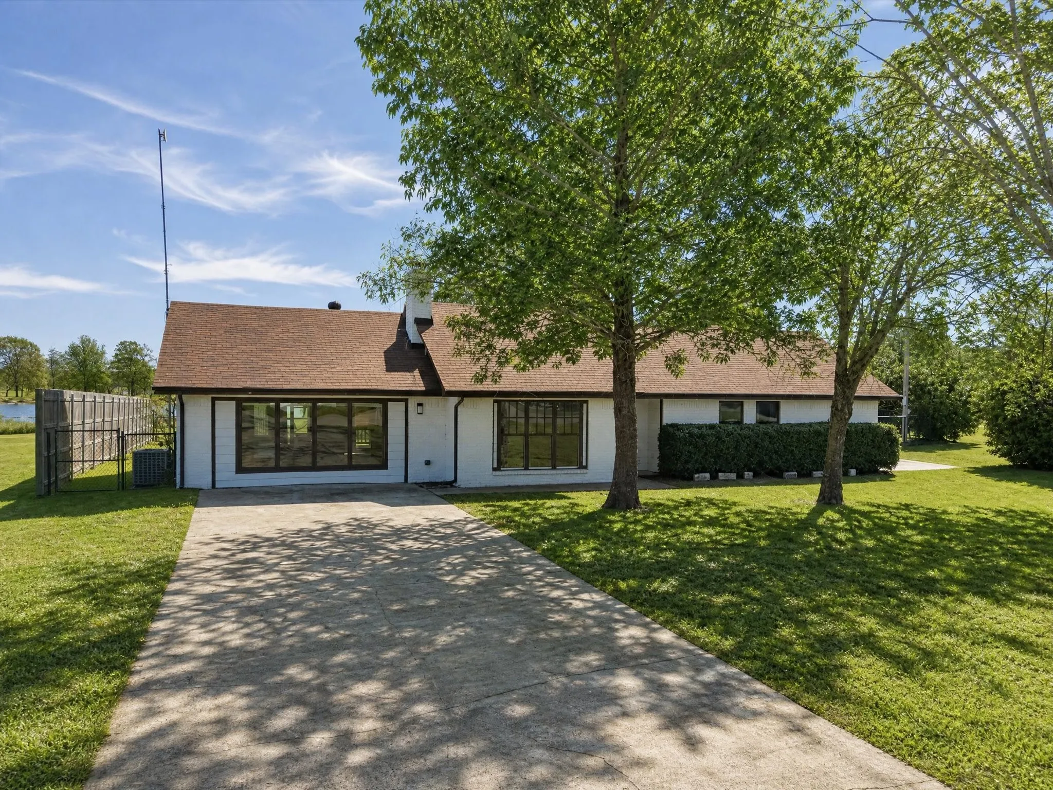 Aerial property overview showcasing a residential structure with an attached driveway, a rear wood deck, and a neighboring vacant lot identified as "LOT 33." The property features established trees and a surrounding green landscape