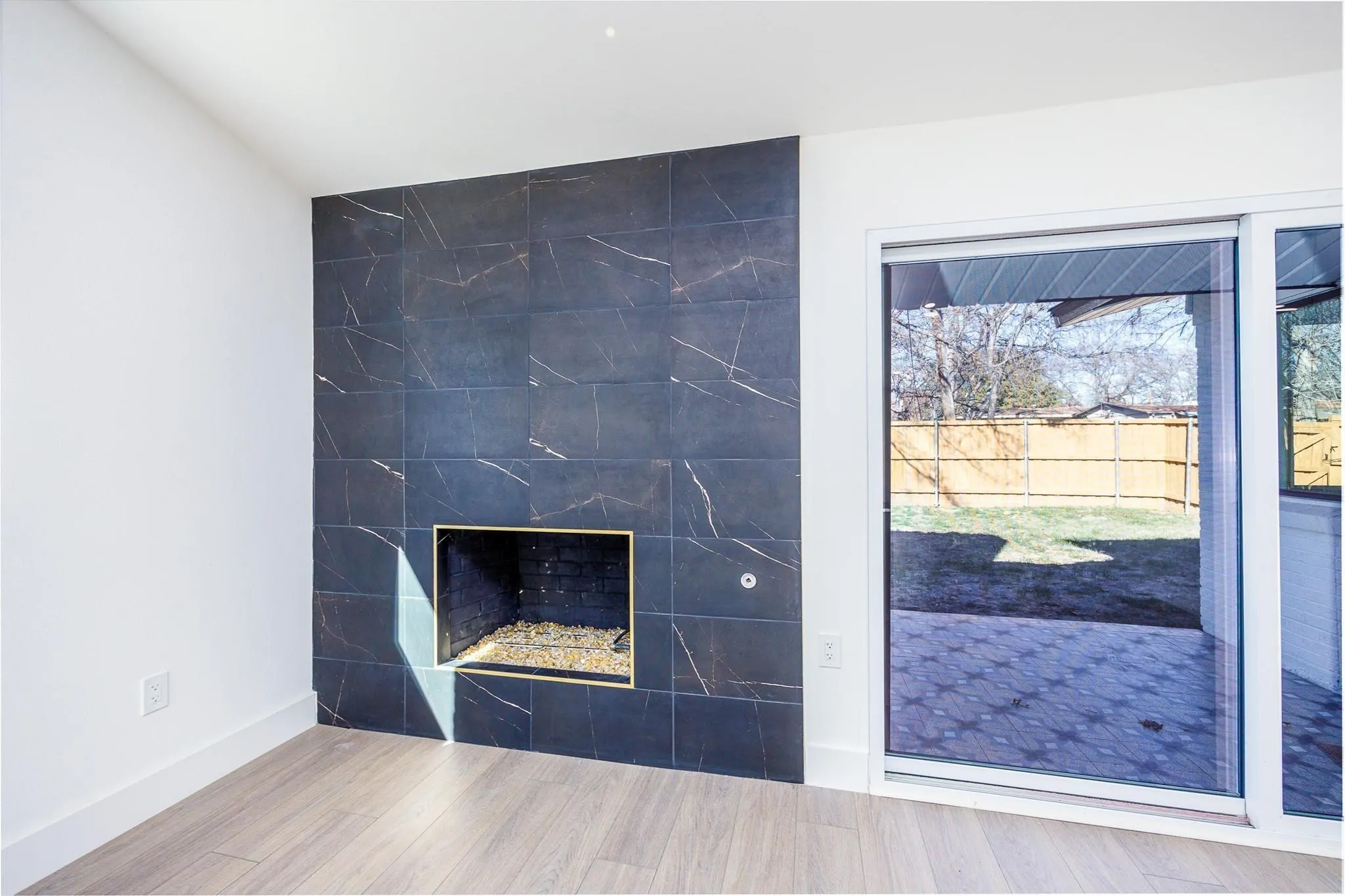 Modern tiled fireplace beside sliders to the backyard