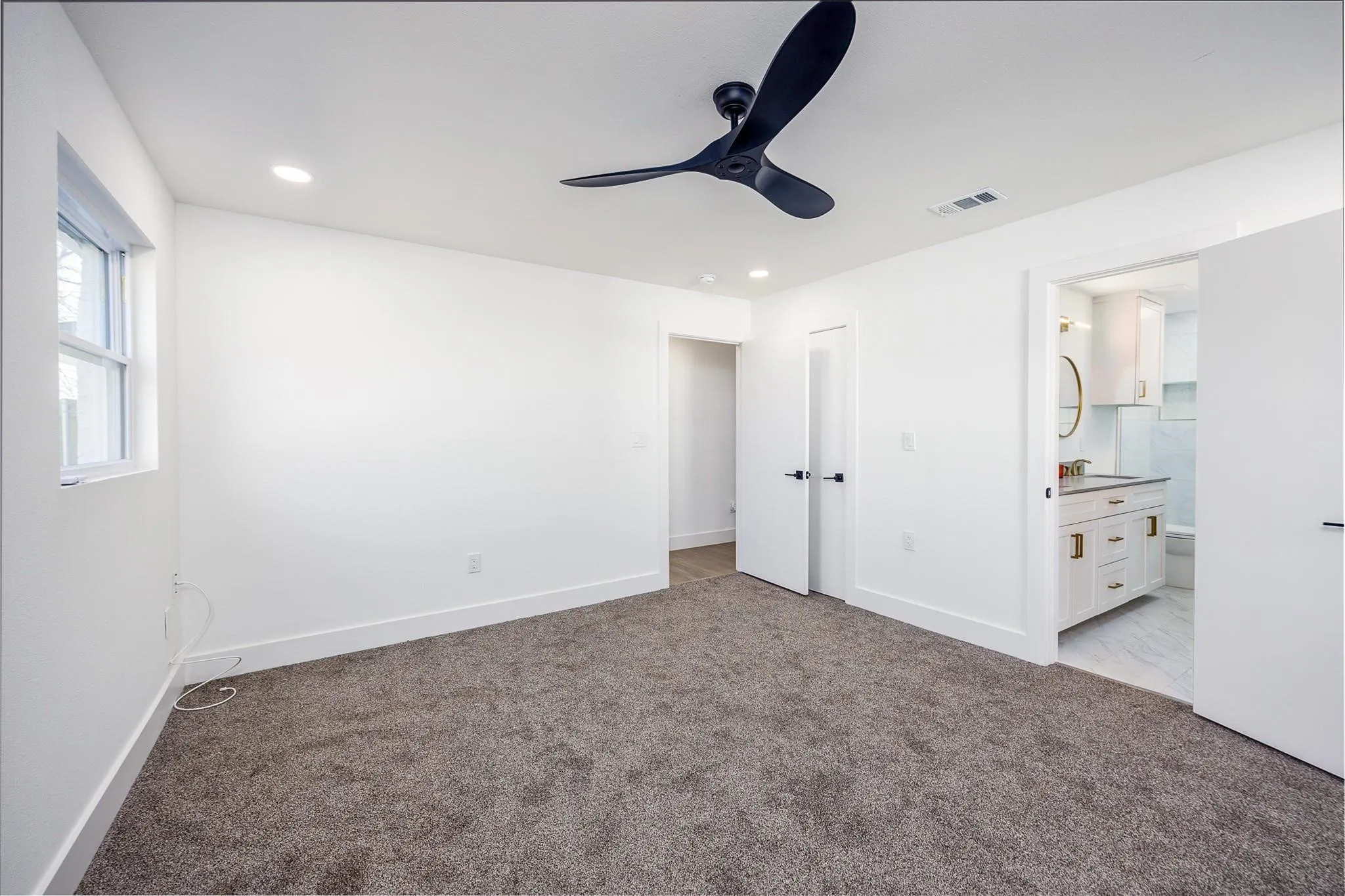 Spacious bedroom with new carpet and ceiling fan