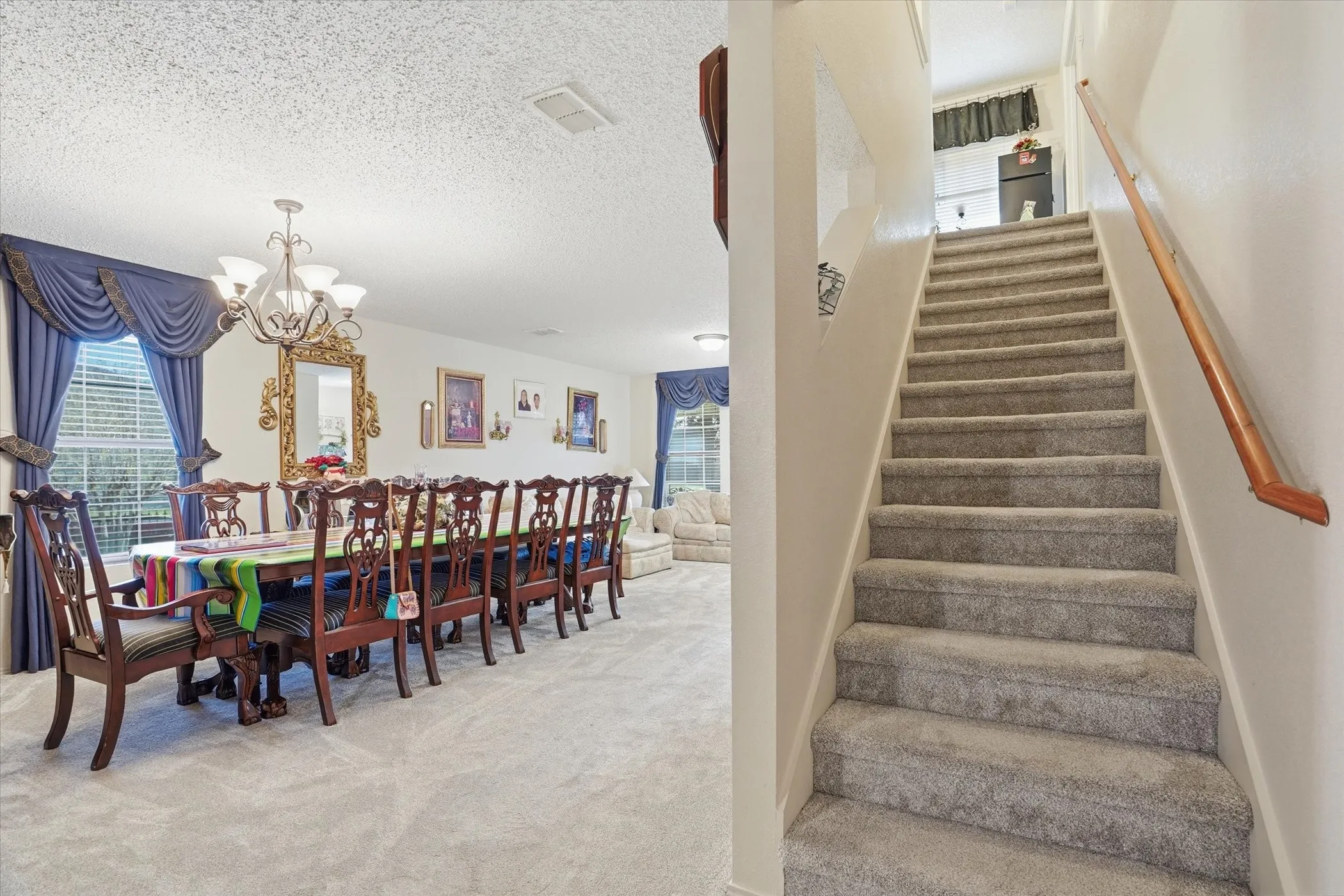Stairs featuring suspended lighting, carpet flooring, and a textured ceiling