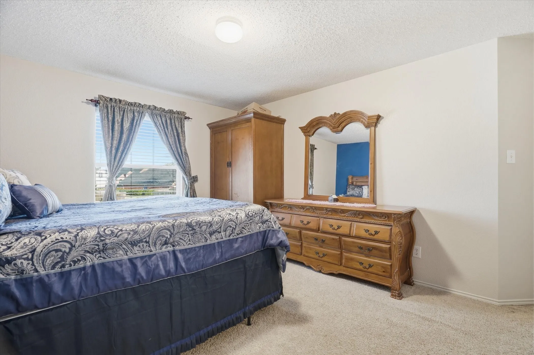 Bedroom featuring light colored carpet and a textured ceiling