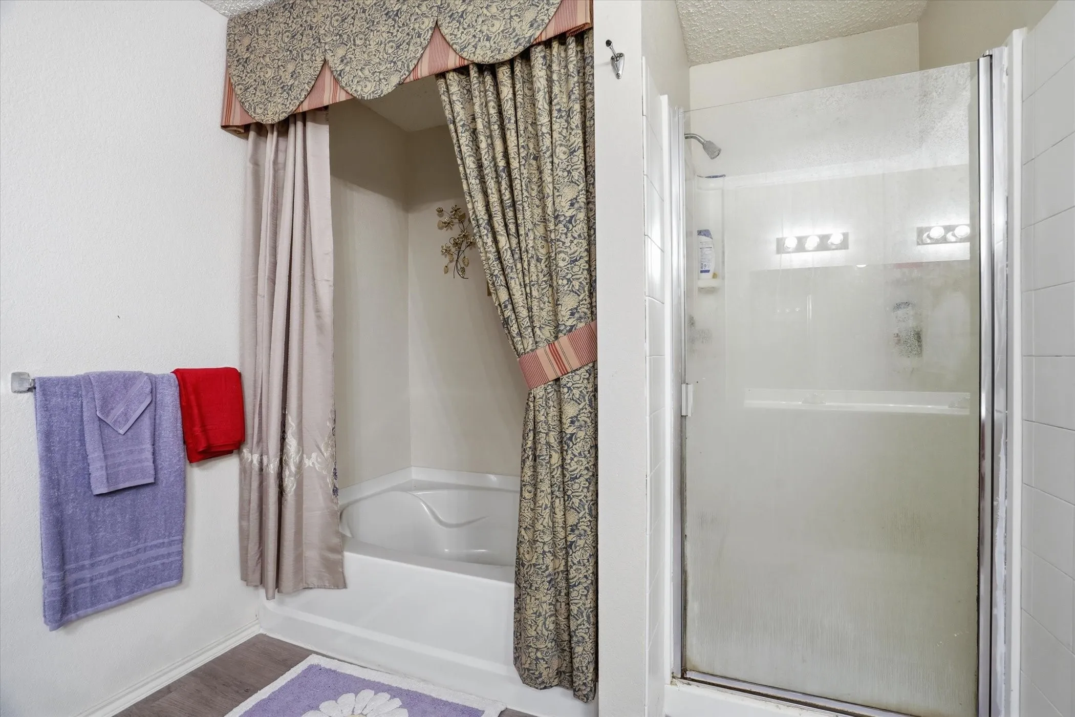 Full bathroom featuring a stall shower, a textured ceiling, and a tub