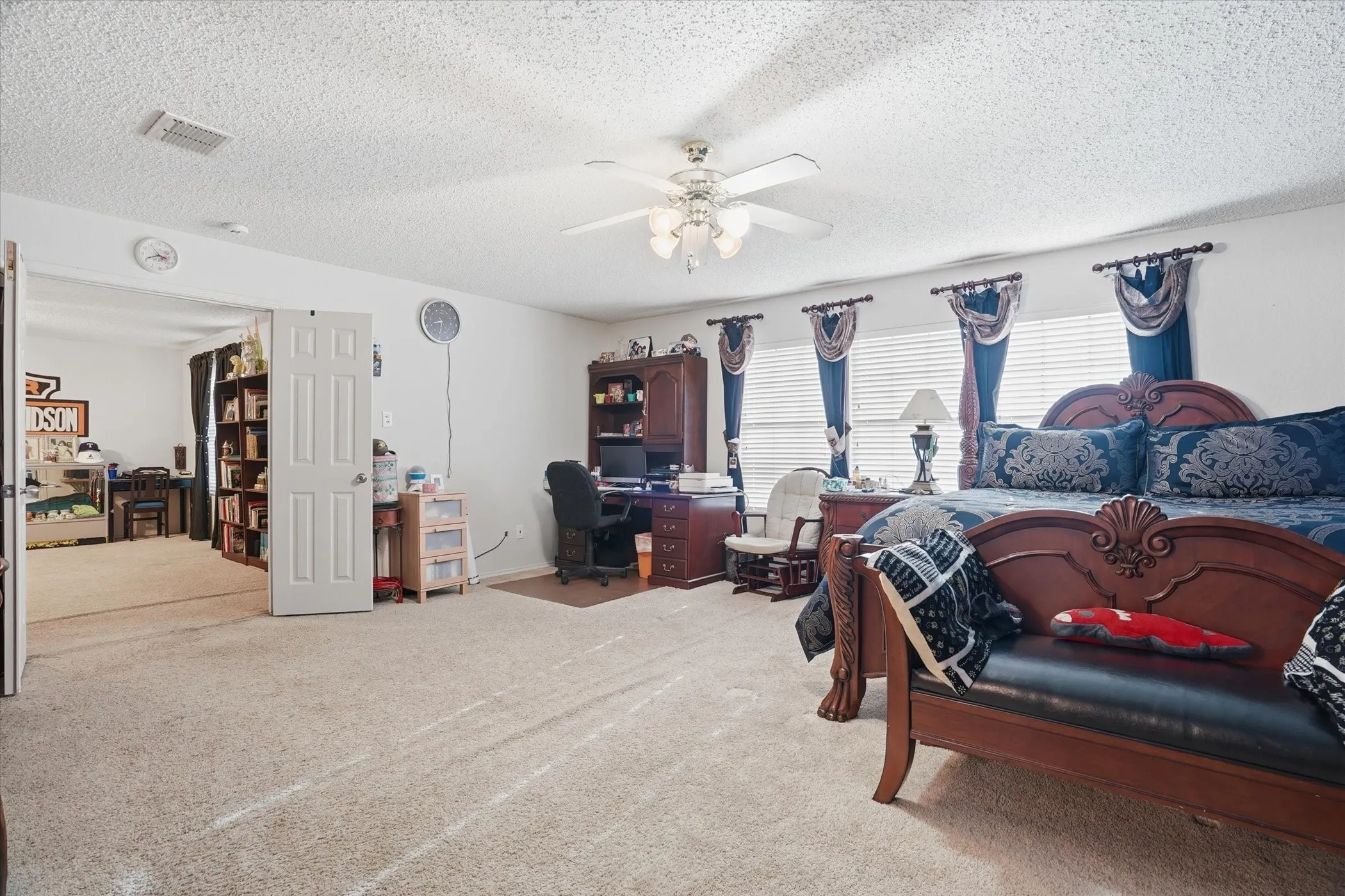 Carpeted bedroom featuring a desk, a ceiling fan, and a textured ceiling