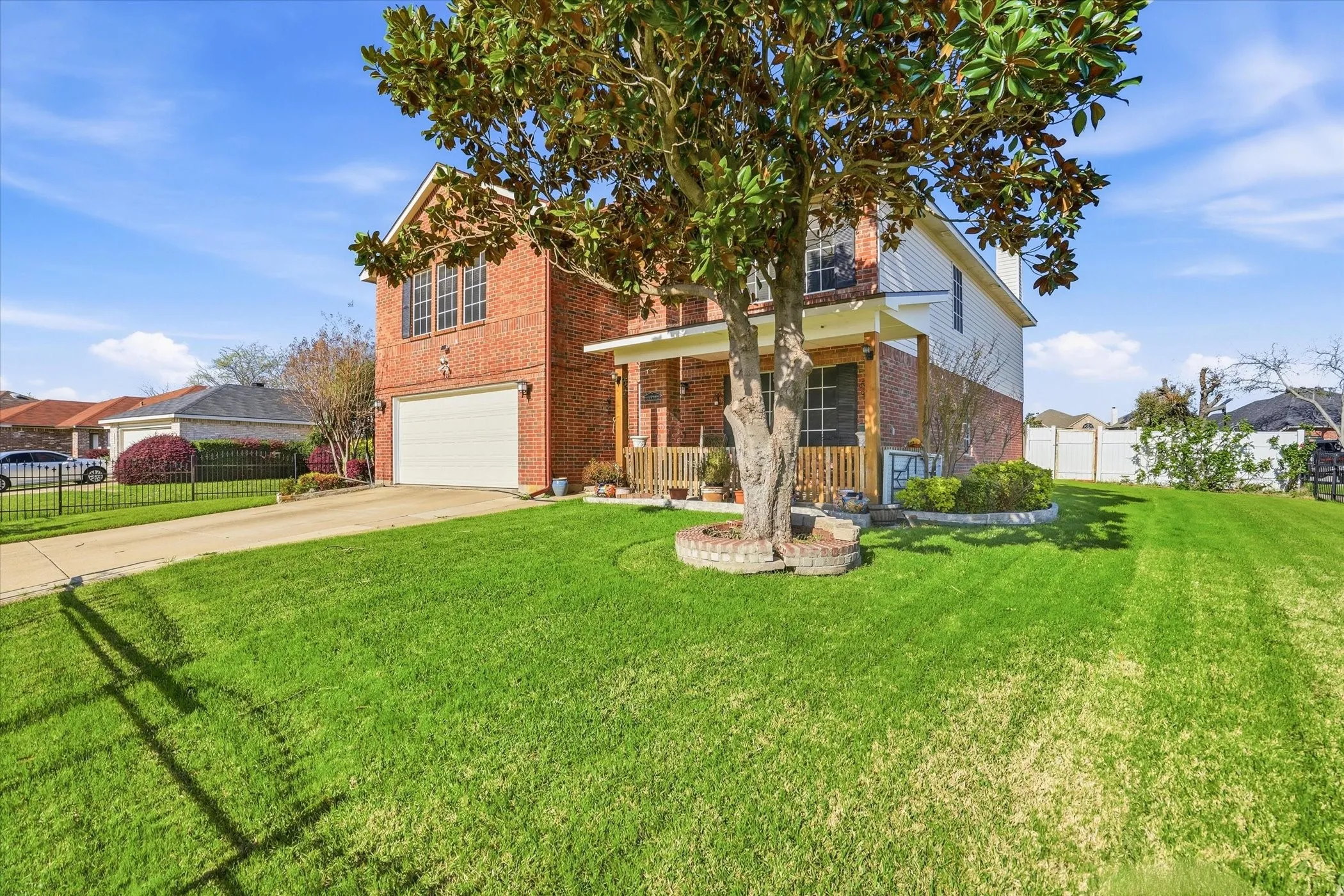 Traditional-style house featuring brick siding, covered porch, driveway, and a garage