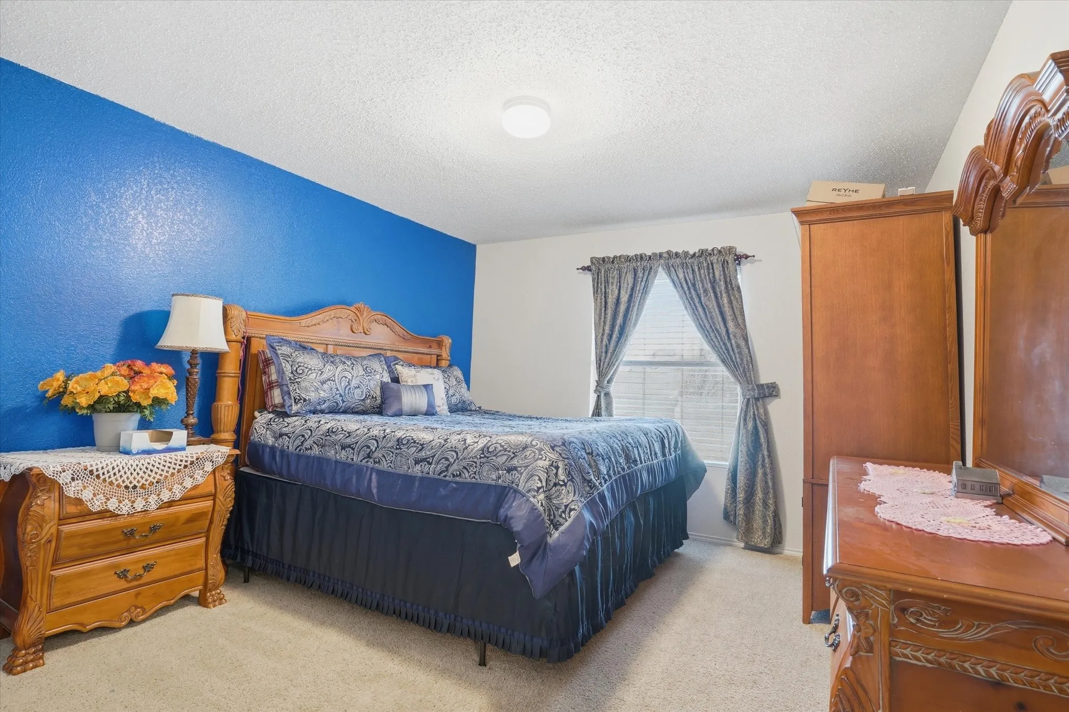 Bedroom with a textured ceiling and light carpet