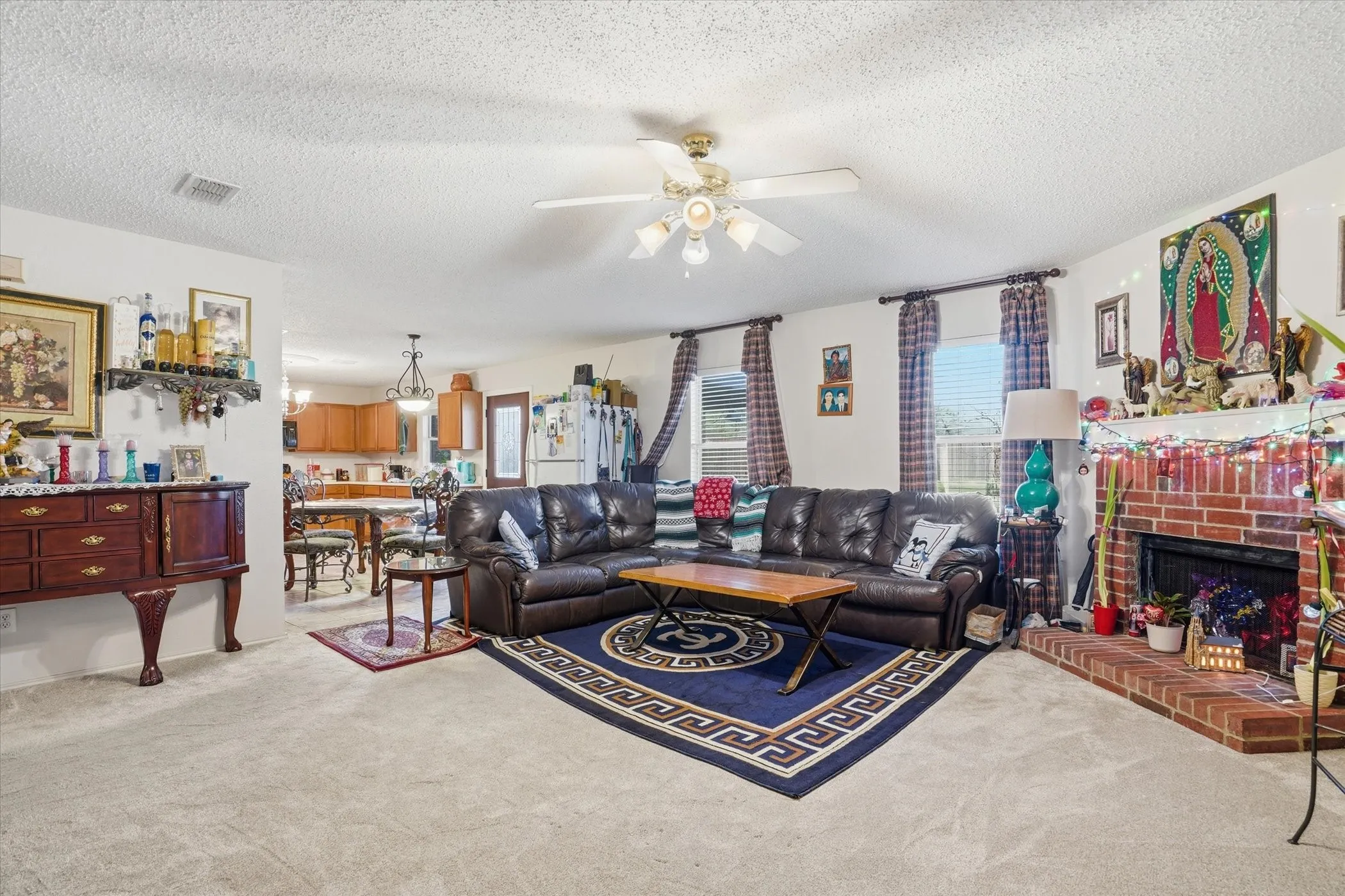Living area with light carpet, plenty of natural light, a textured ceiling, and ceiling fan