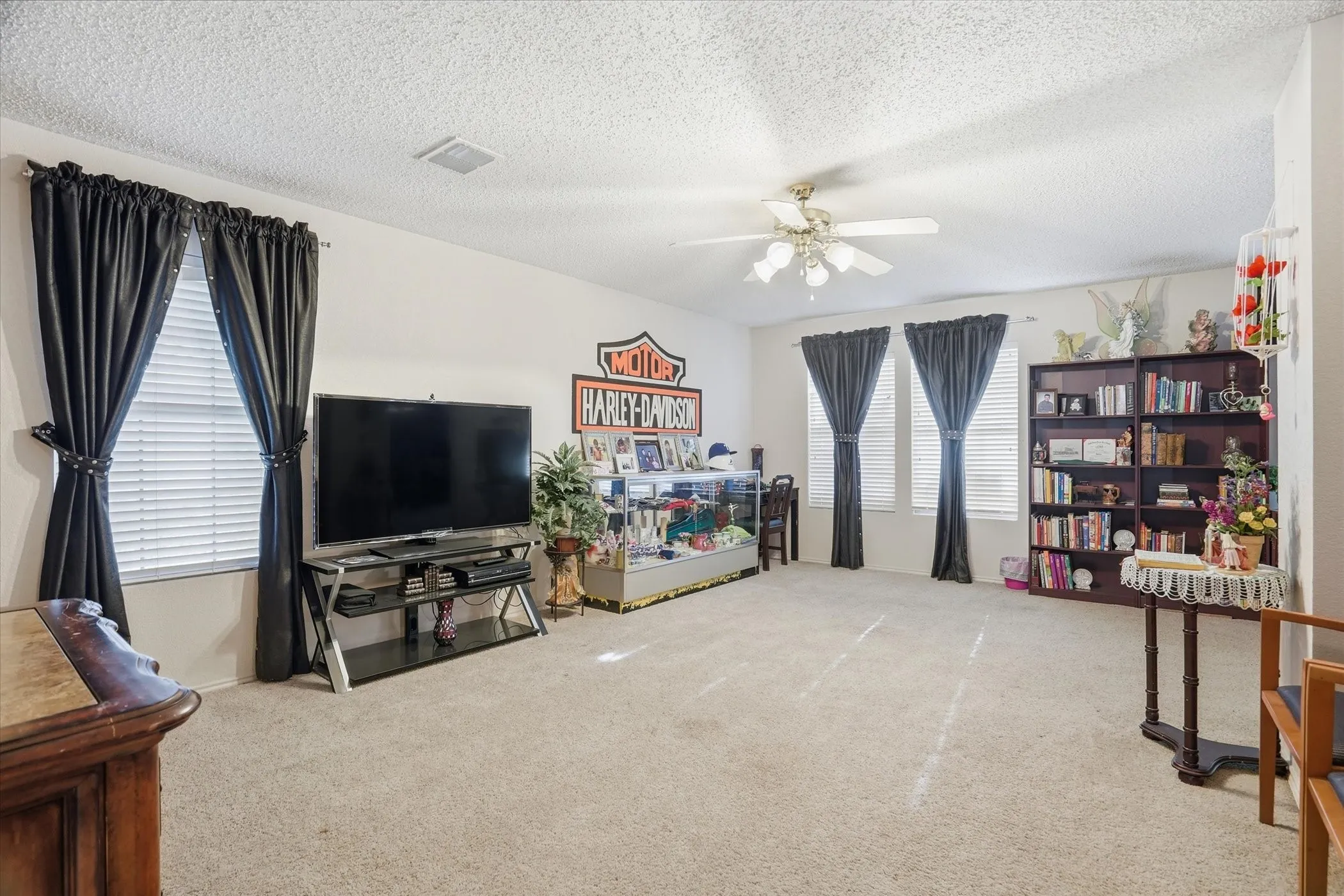 Living area featuring light colored carpet, a textured ceiling, and a ceiling fan
