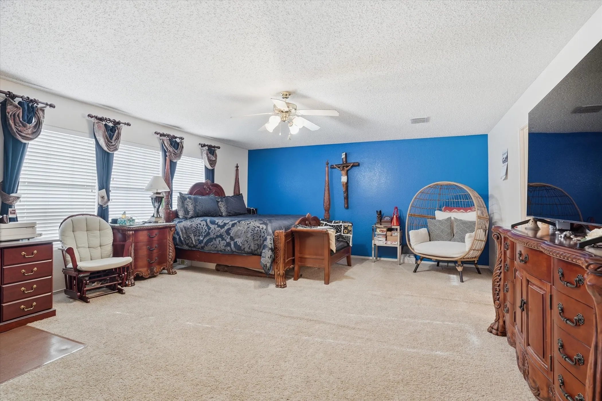 Bedroom with light carpet, ceiling fan, and a textured ceiling