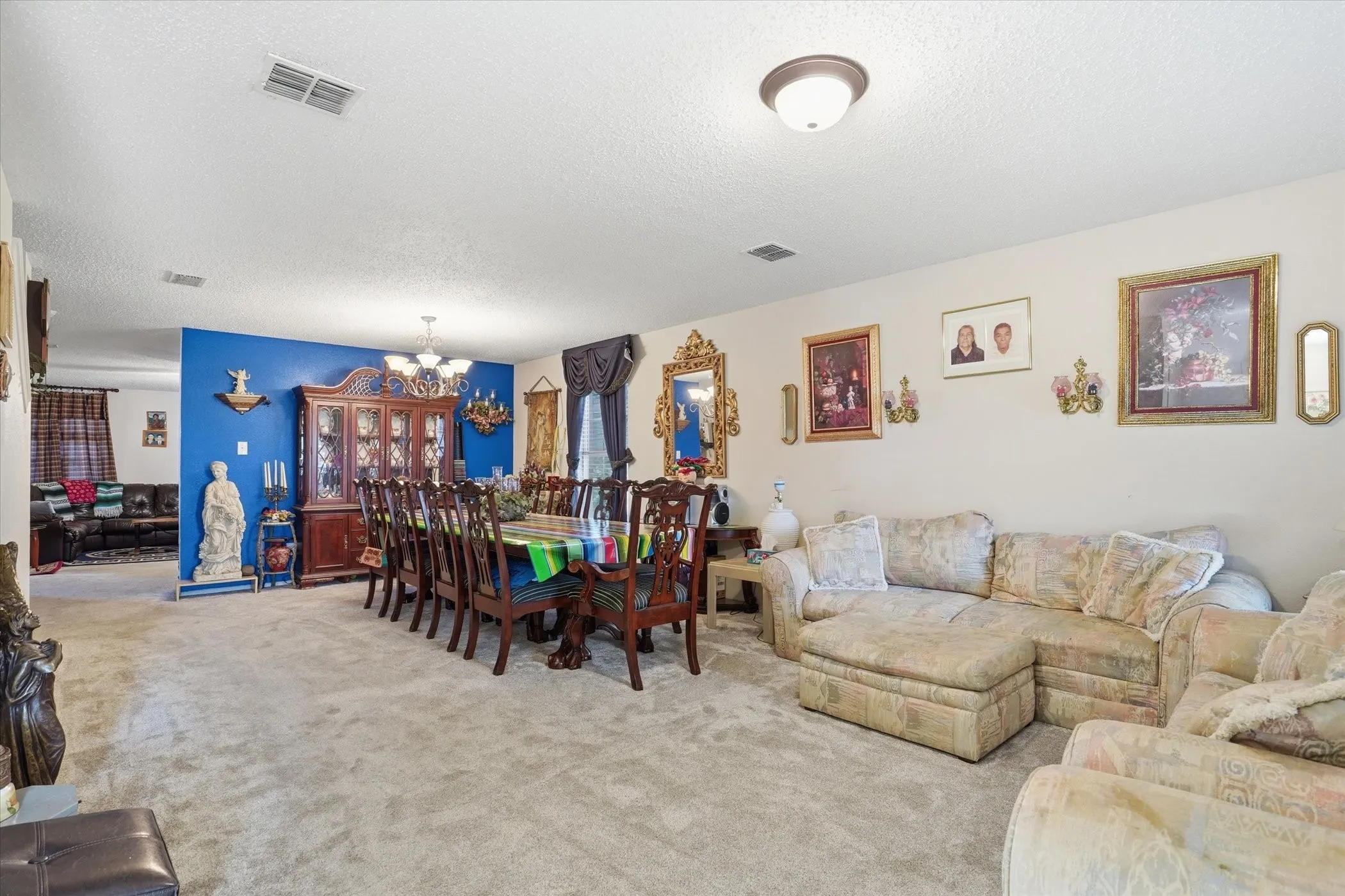 Living area featuring a textured ceiling, carpet, and a chandelier