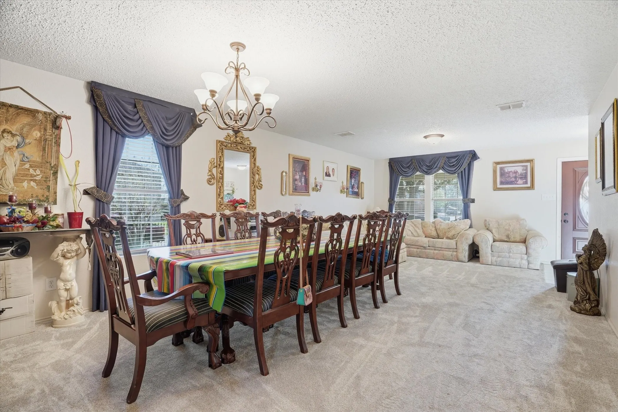 Dining room with suspended lighting, a textured ceiling, and light colored carpet