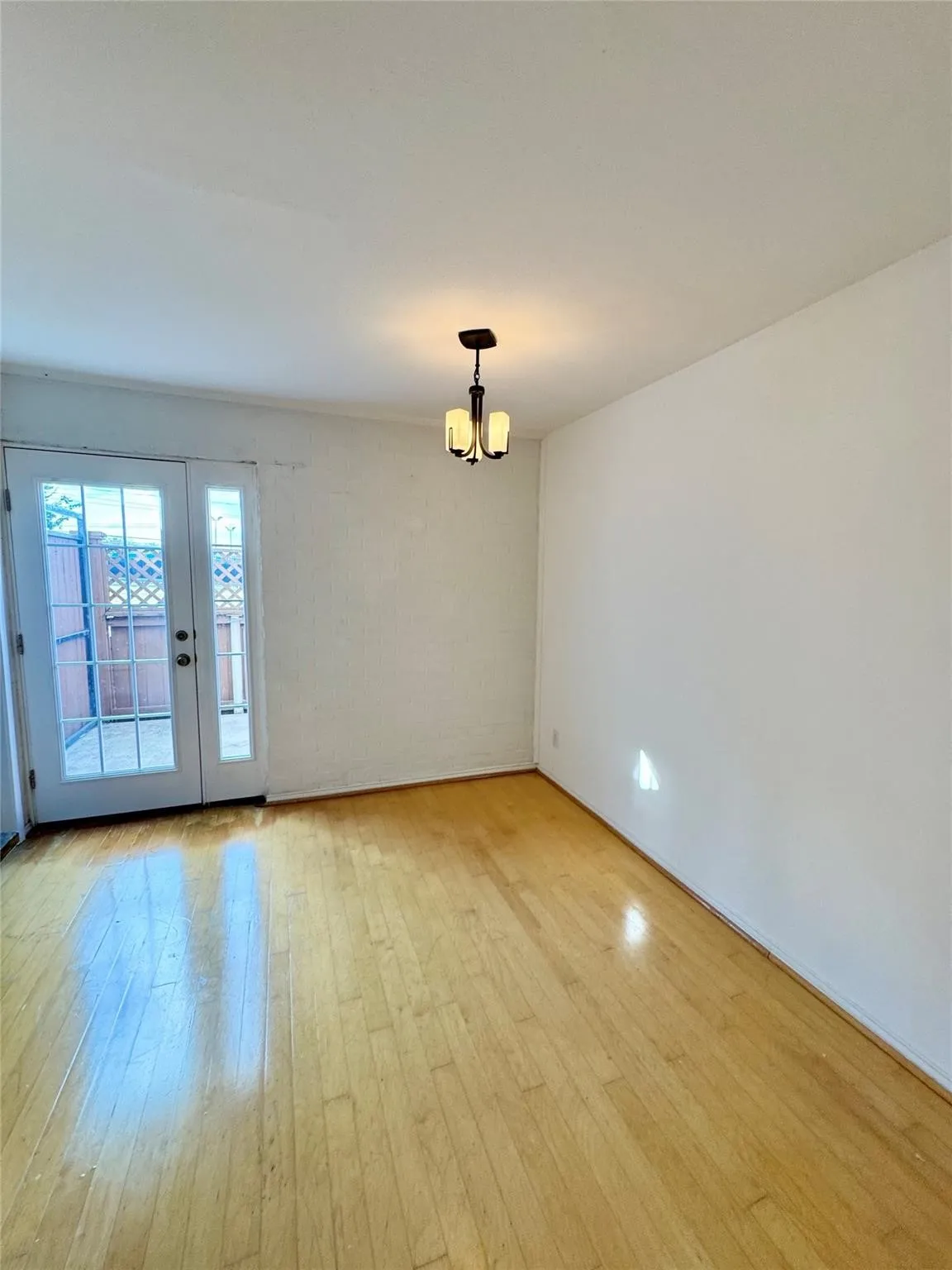 Unfurnished room featuring light wood-type flooring, a chandelier, and french doors