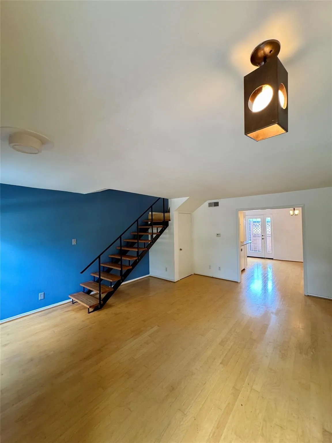 Unfurnished living room featuring wood finished floors and french doors