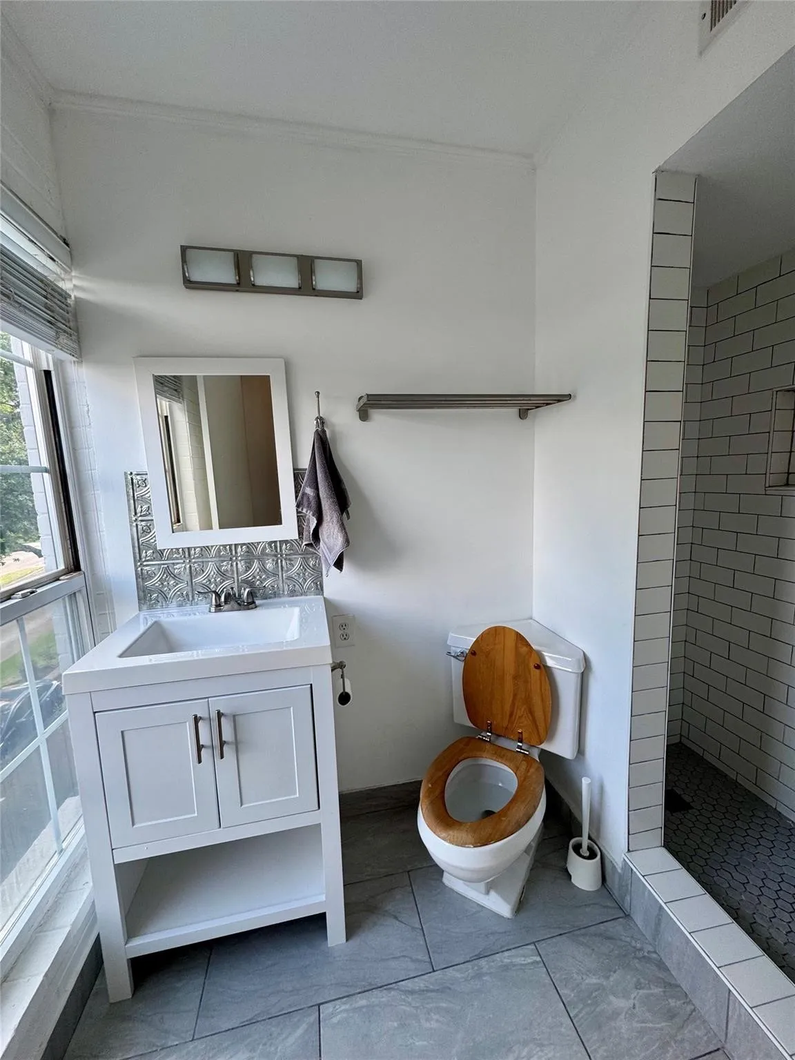 Bathroom with vanity, a tile shower, and crown molding