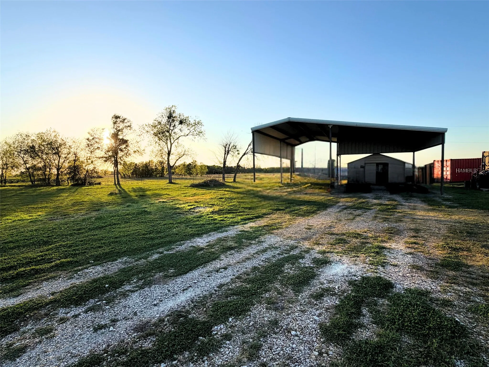 Yard at dusk with driveway, a yard, a storage shed, and a detached carport