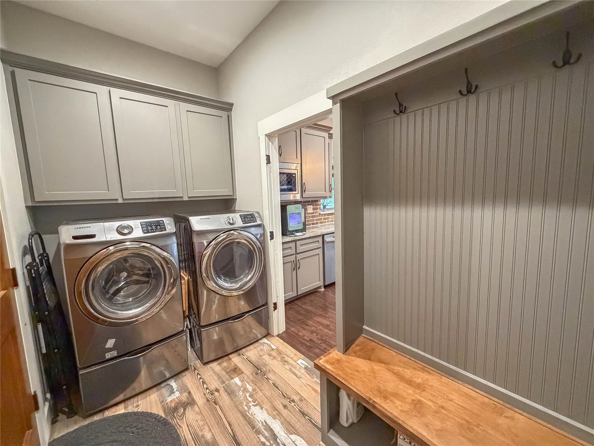 Laundry area with light wood finished floors, washer and clothes dryer, and cabinet space