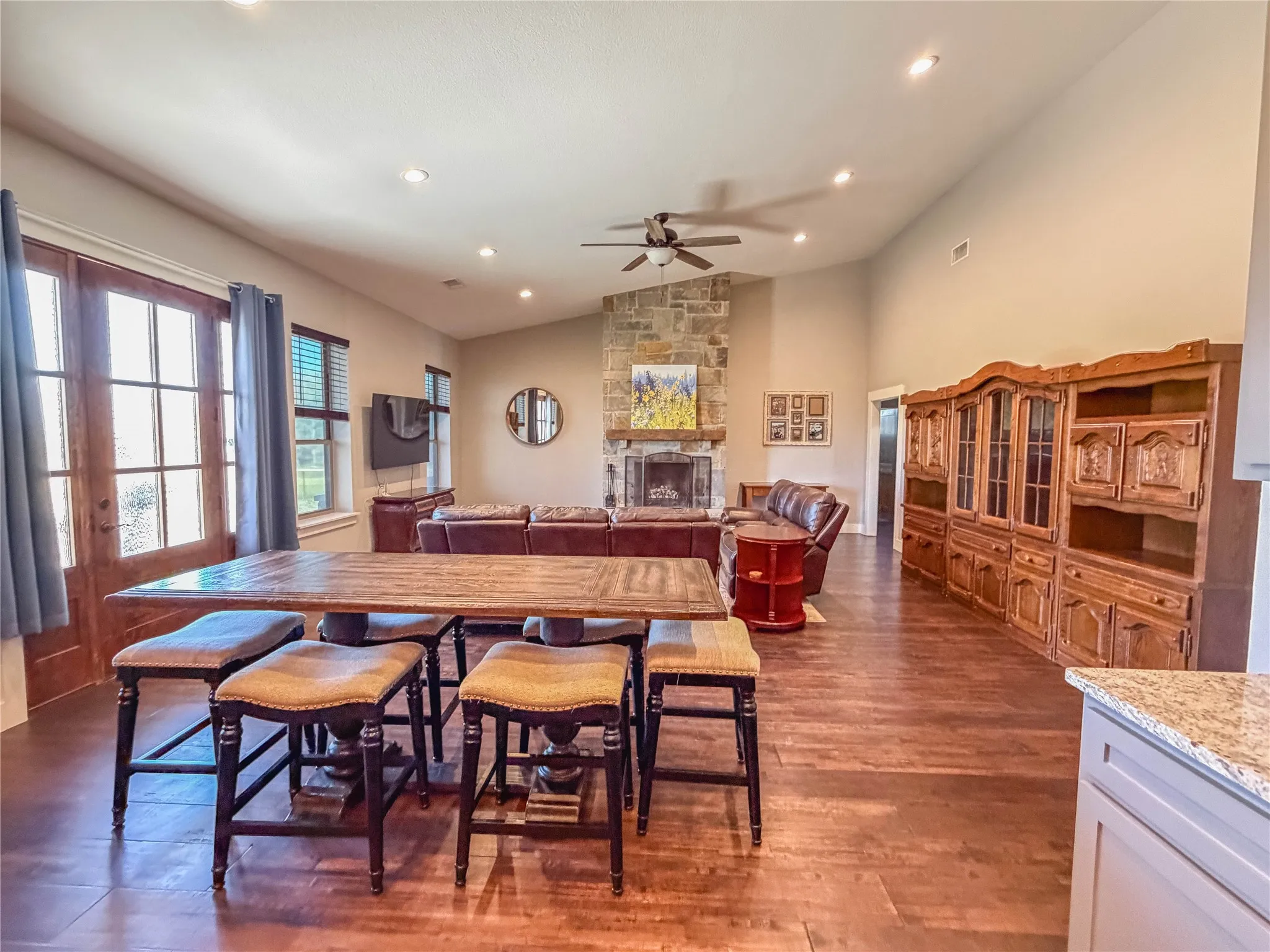 Dining area featuring a stone fireplace, dark wood-type flooring, ceiling fan, lofted ceiling, and recessed lighting
