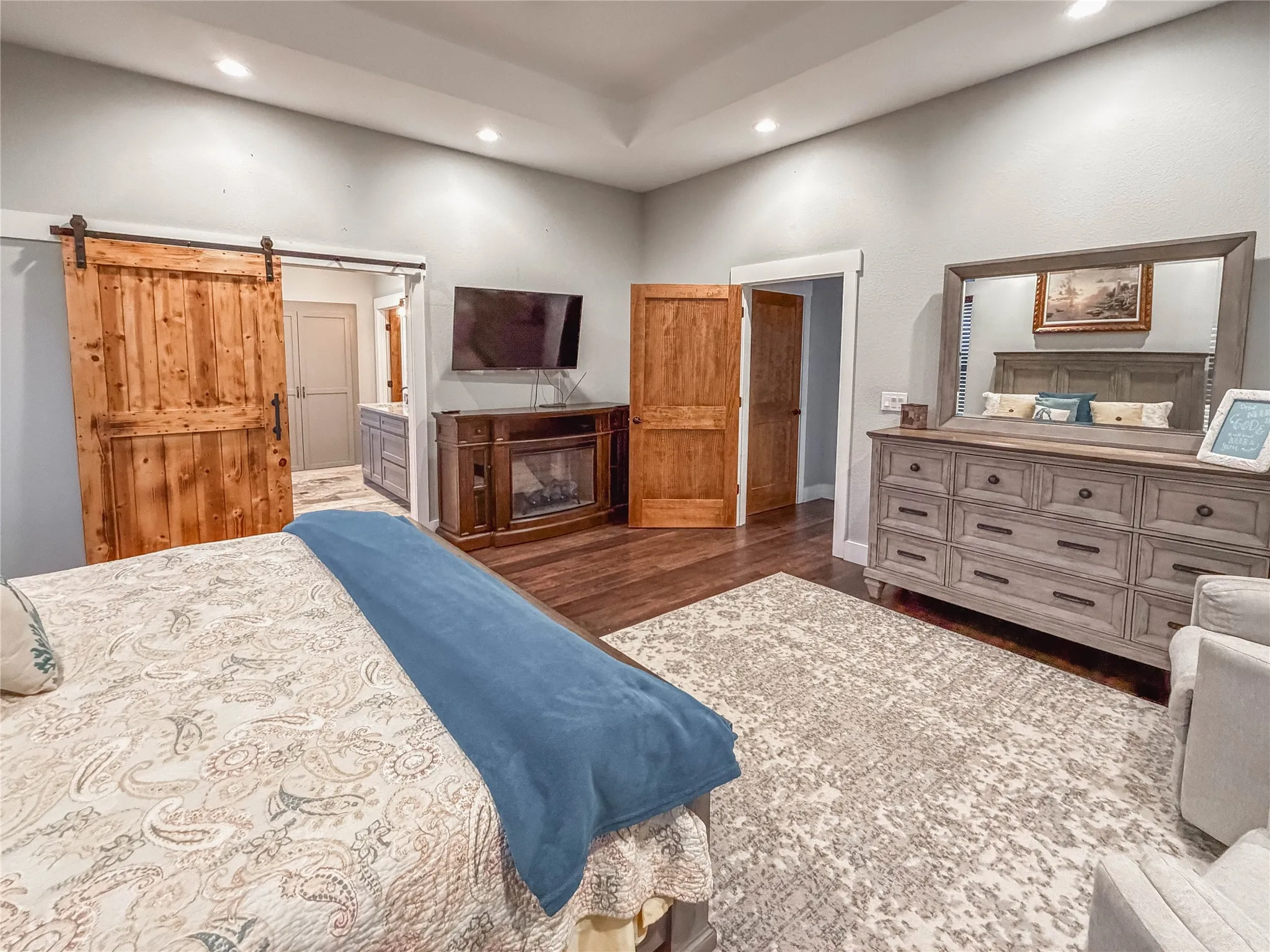 Bedroom with dark wood-type flooring, ensuite bath, recessed lighting, and a barn door