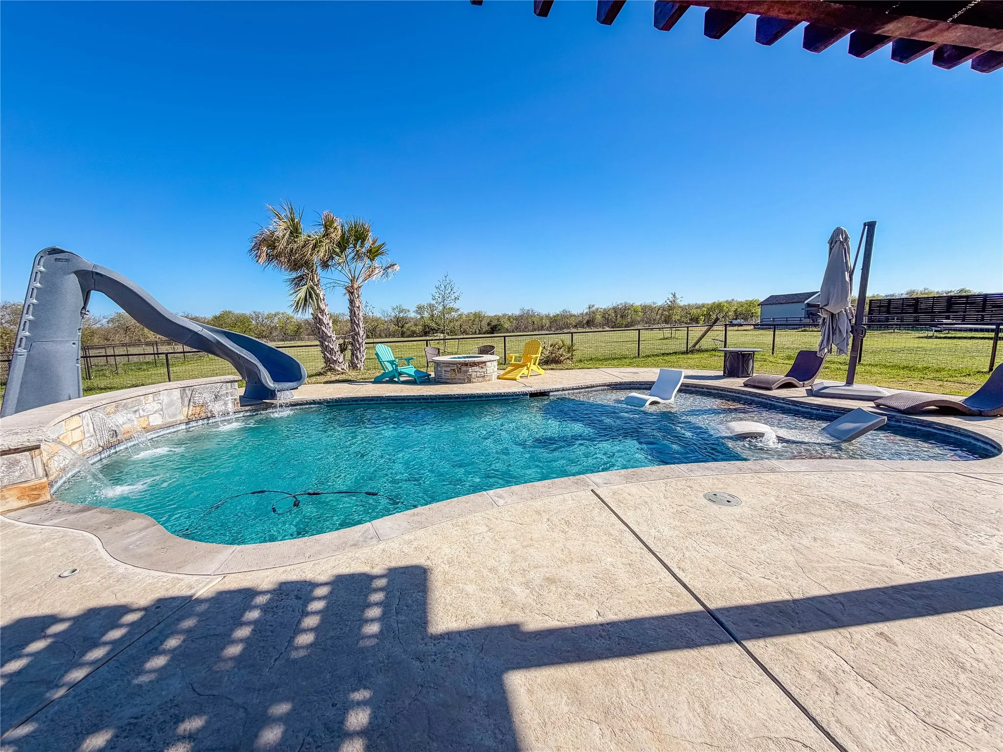 View of pool featuring a water slide and patio surround