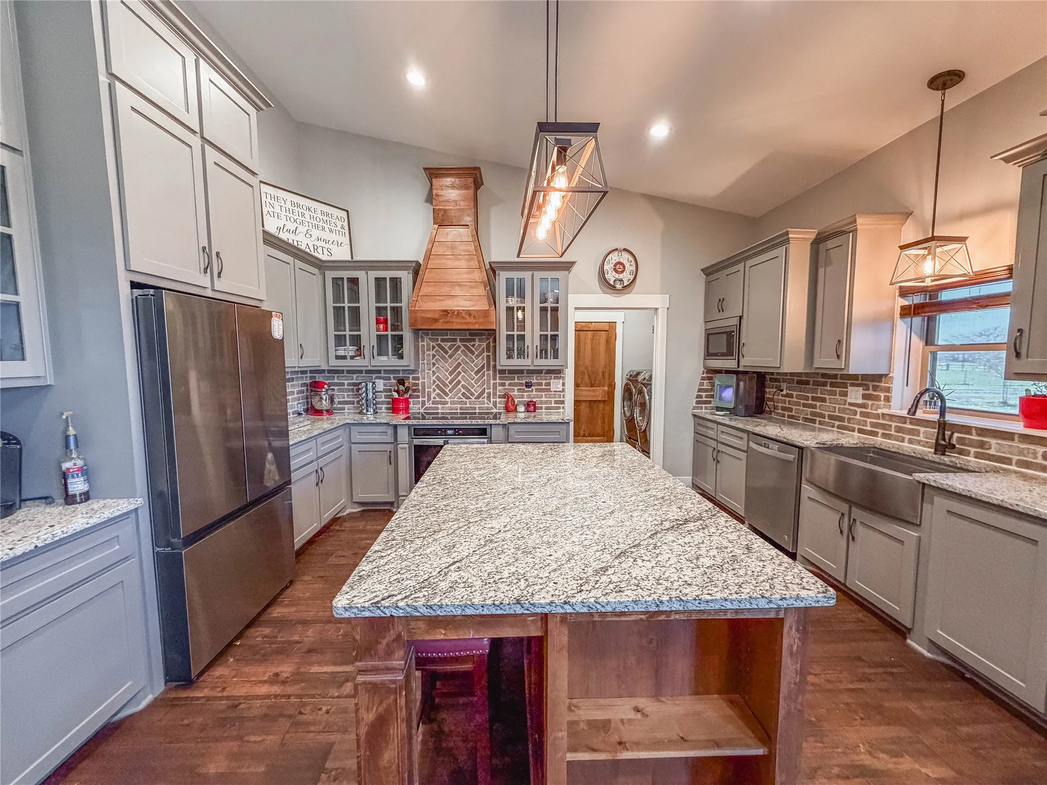 Kitchen with gray cabinetry, light stone countertops, and glass insert cabinets