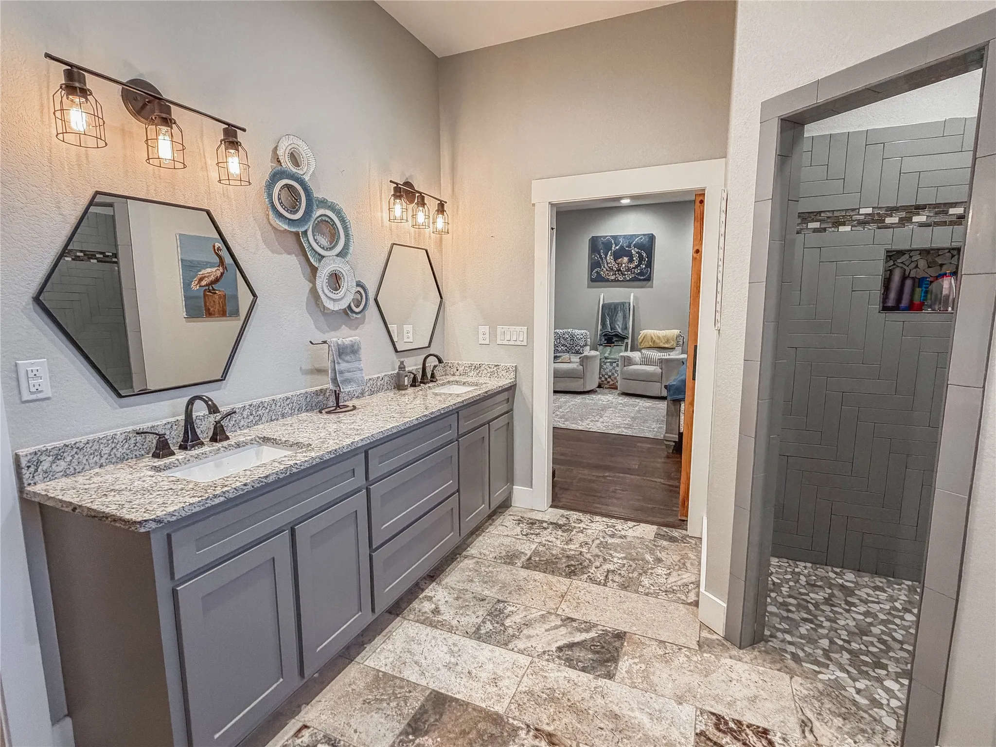 Ensuite bathroom featuring double vanity, light stone finish floors, and a walk in shower