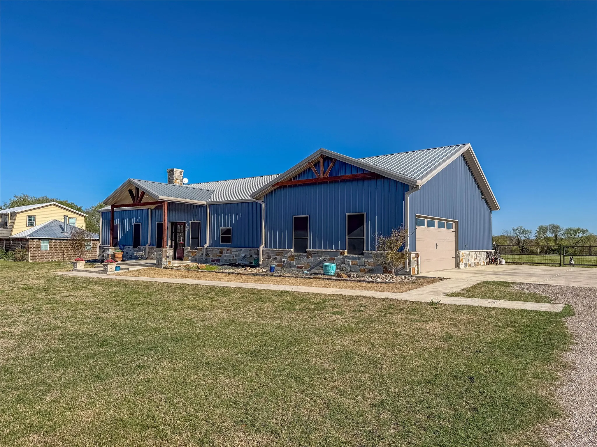 View of front of home with a porch, driveway, a chimney, board and batten siding, and a garage