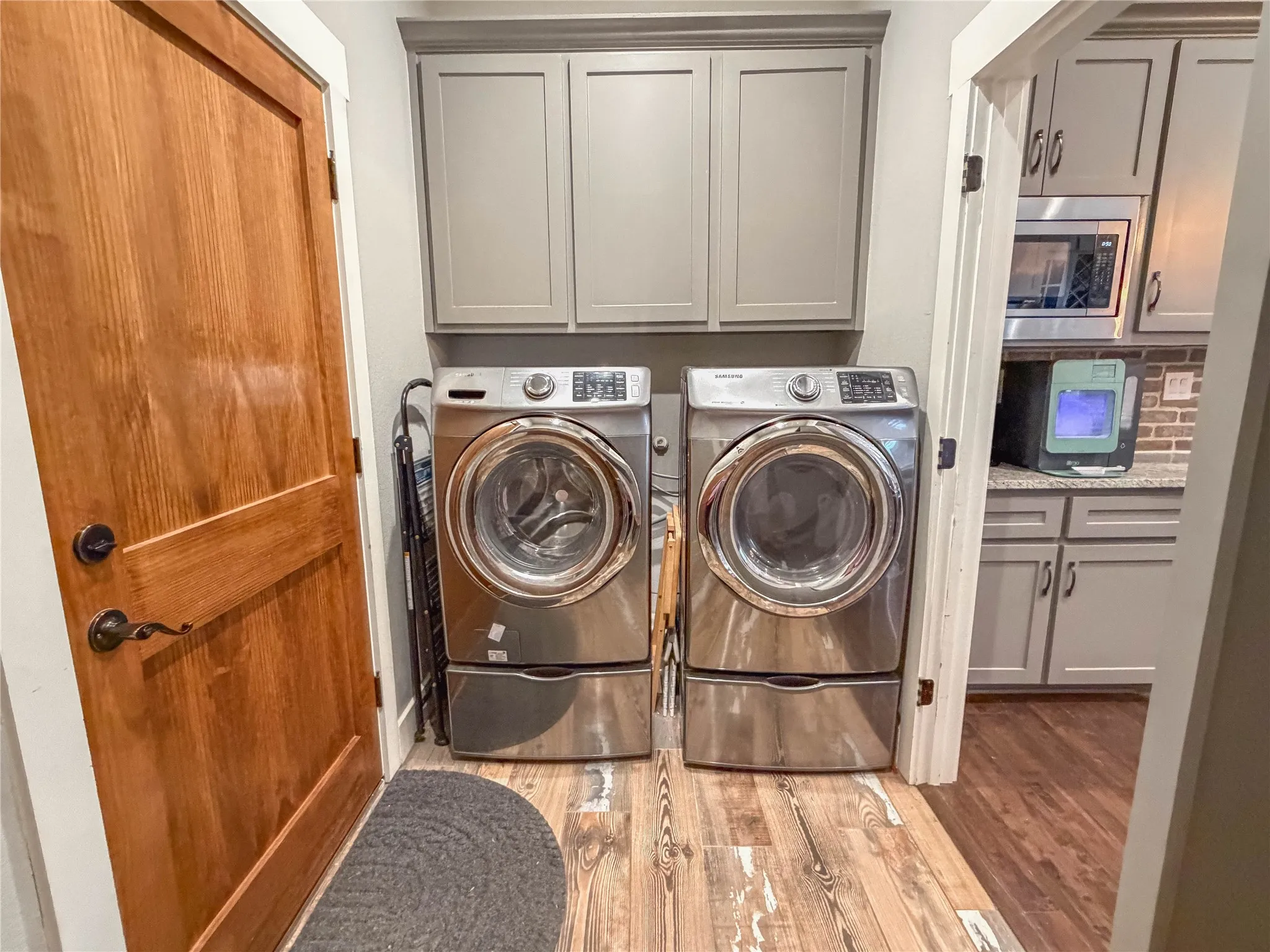 Laundry room with light wood-type flooring, washing machine and dryer, and cabinet space
