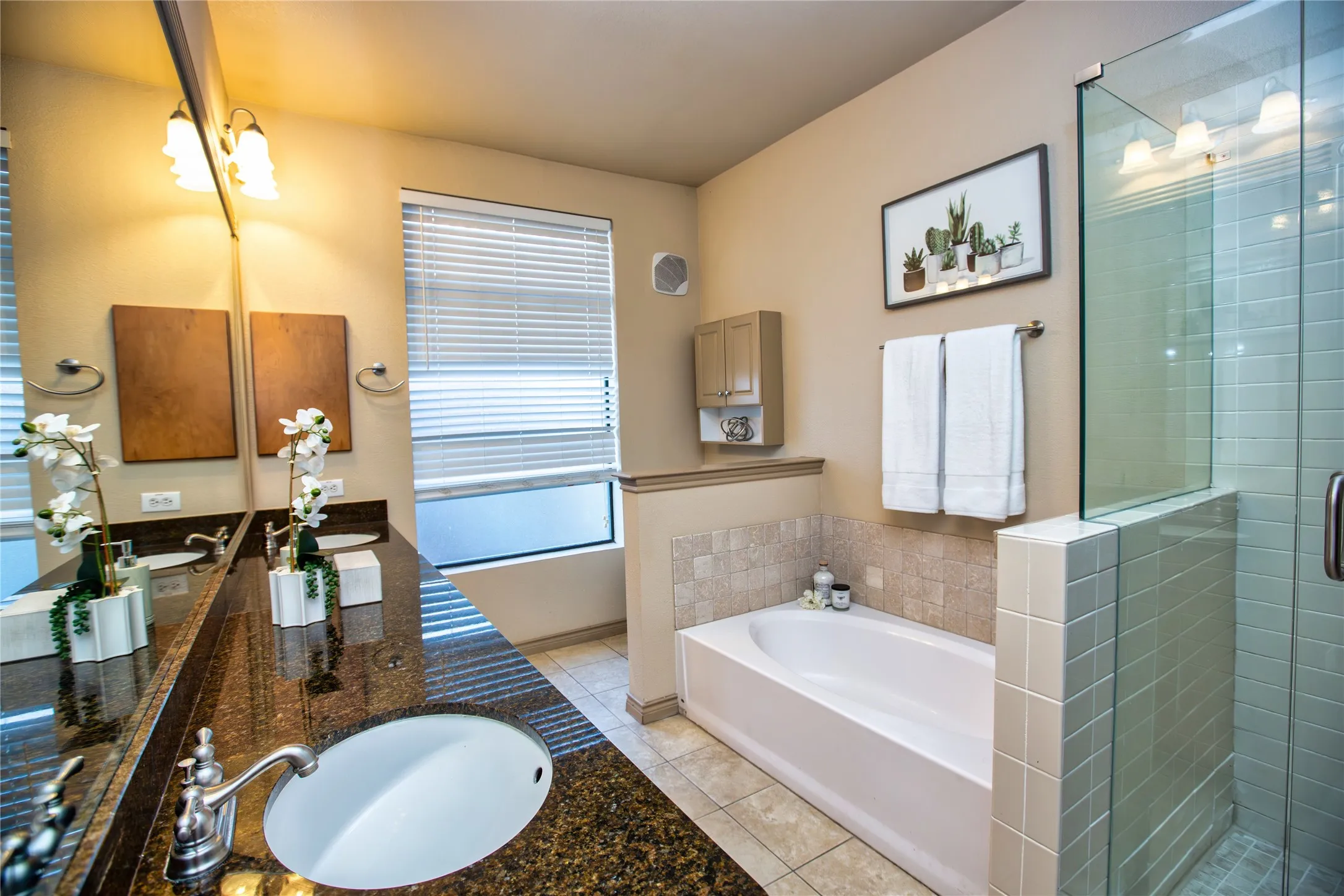 Full bathroom featuring double vanity, a shower stall, a garden tub, and light tile patterned floors