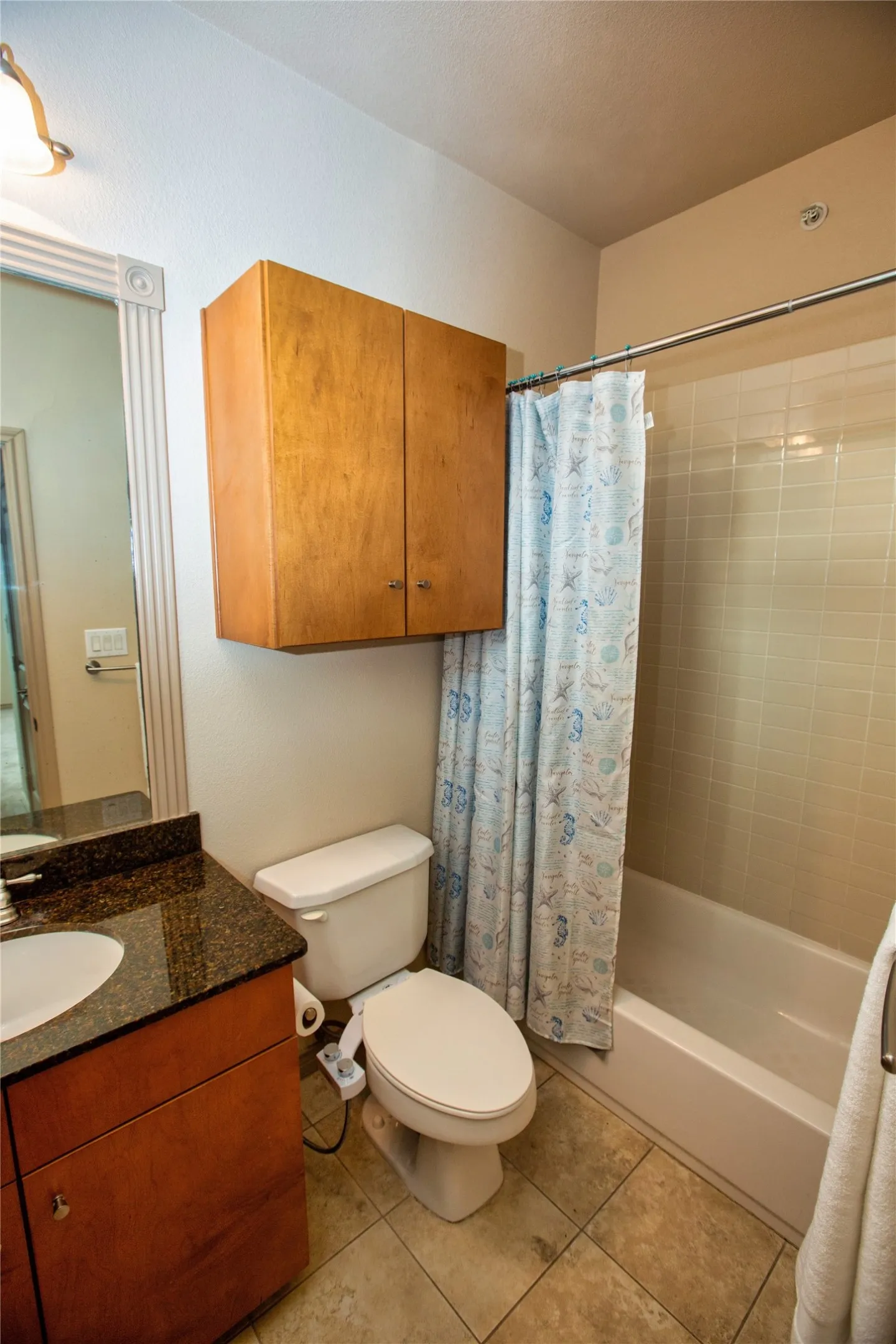 Ensuite bathroom with vanity, shower / bath combination with curtain, and light tile patterned flooring