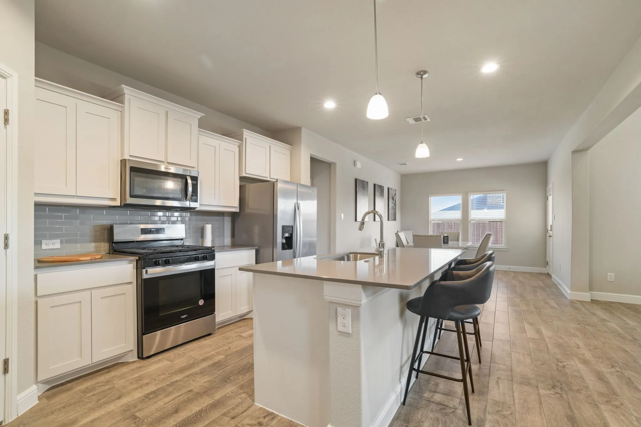 Kitchen with stainless steel appliances, a kitchen bar, a kitchen island with sink, tasteful backsplash, and light wood finished floors