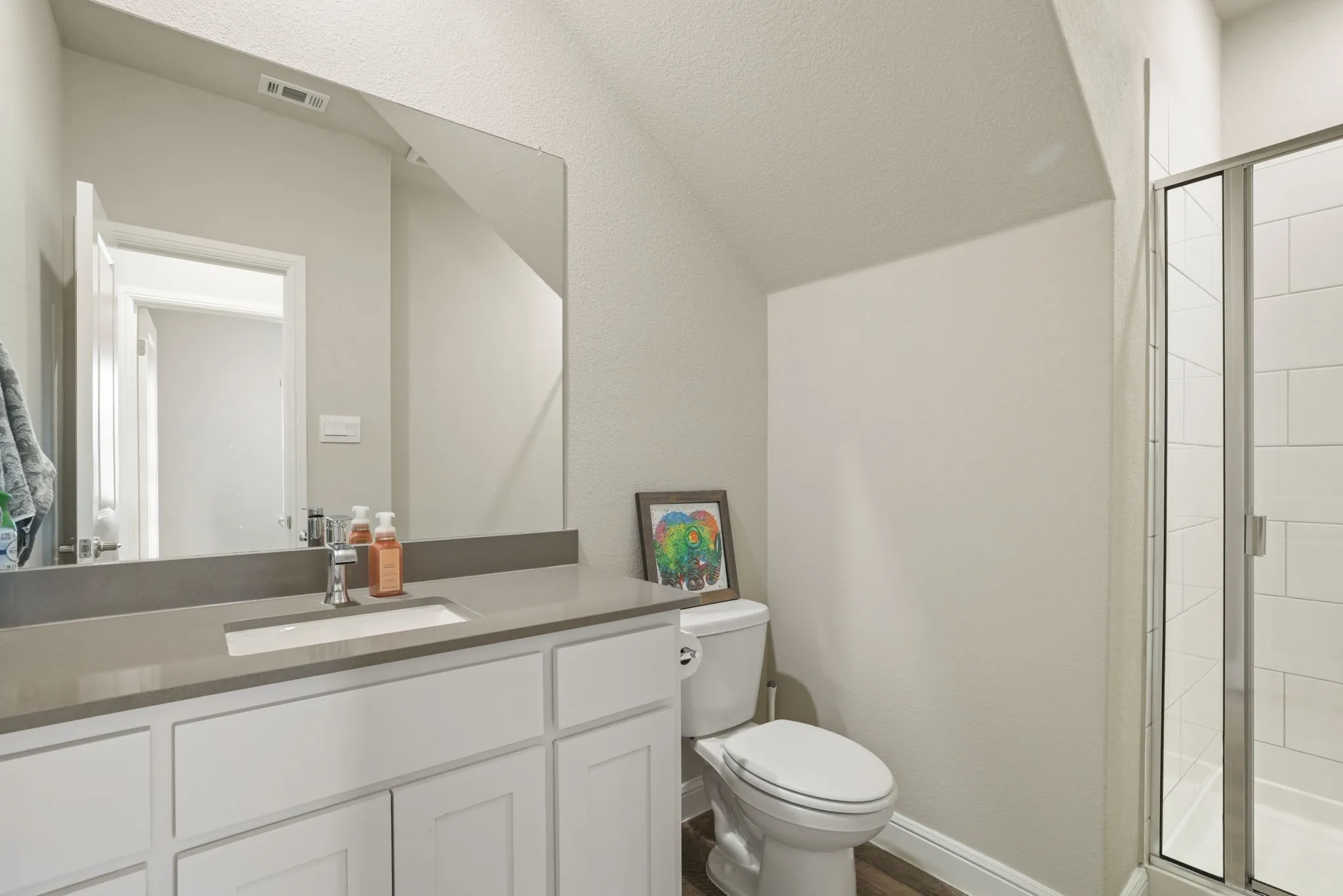 Full bathroom with a stall shower, vanity, and lofted ceiling