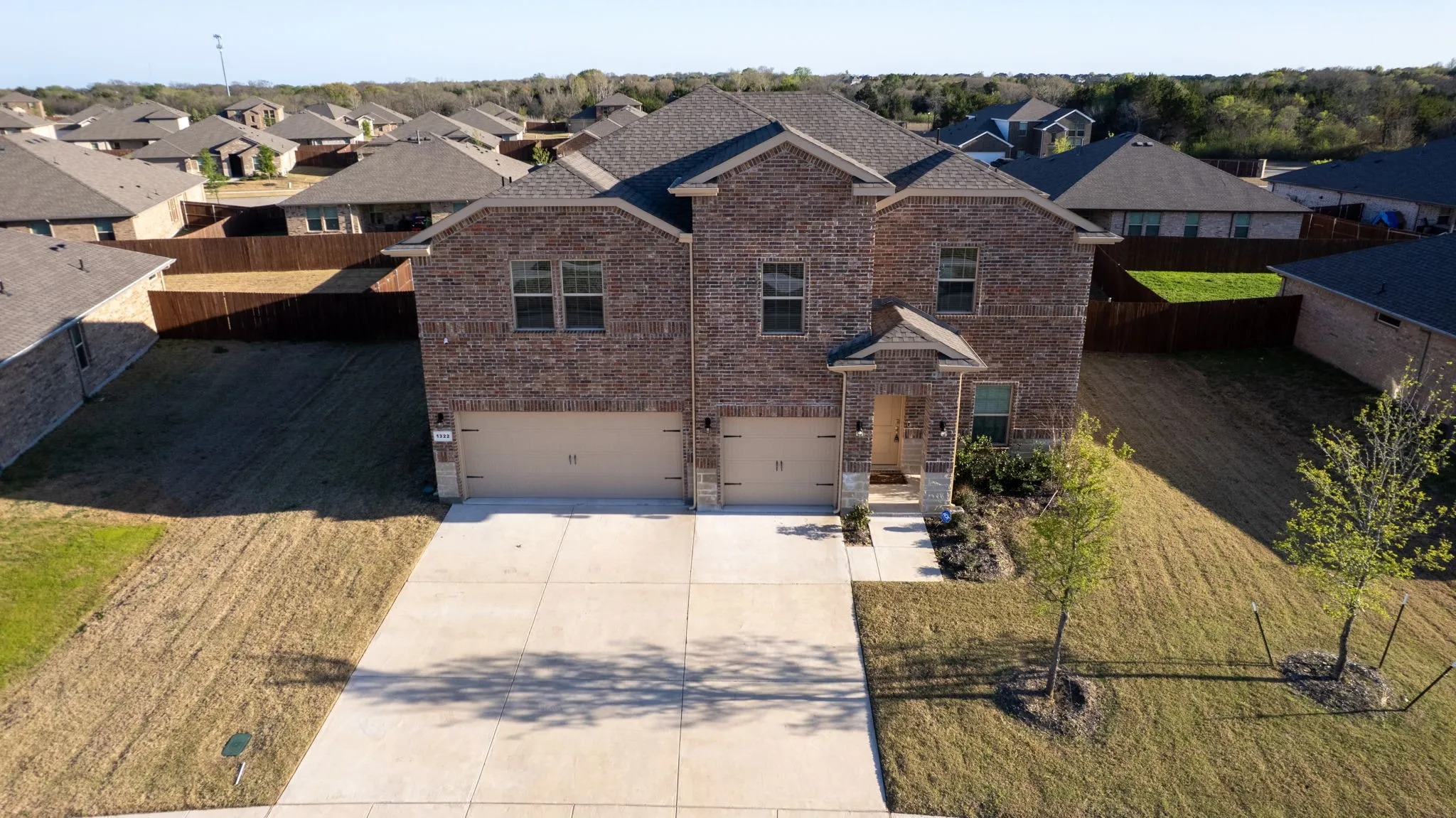 View of front of home with brick siding, an attached garage, driveway, and a residential view