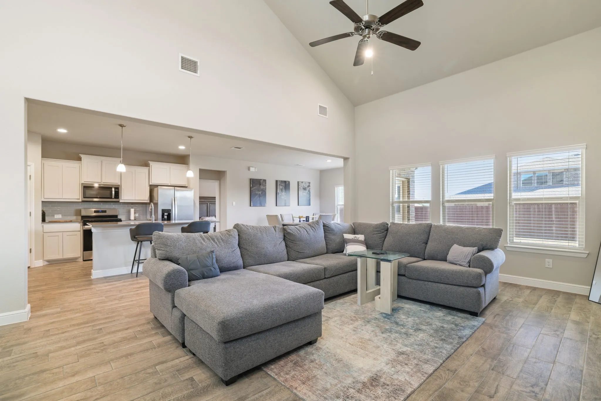 Living area with light wood-type flooring, ceiling fan, and lofted ceiling