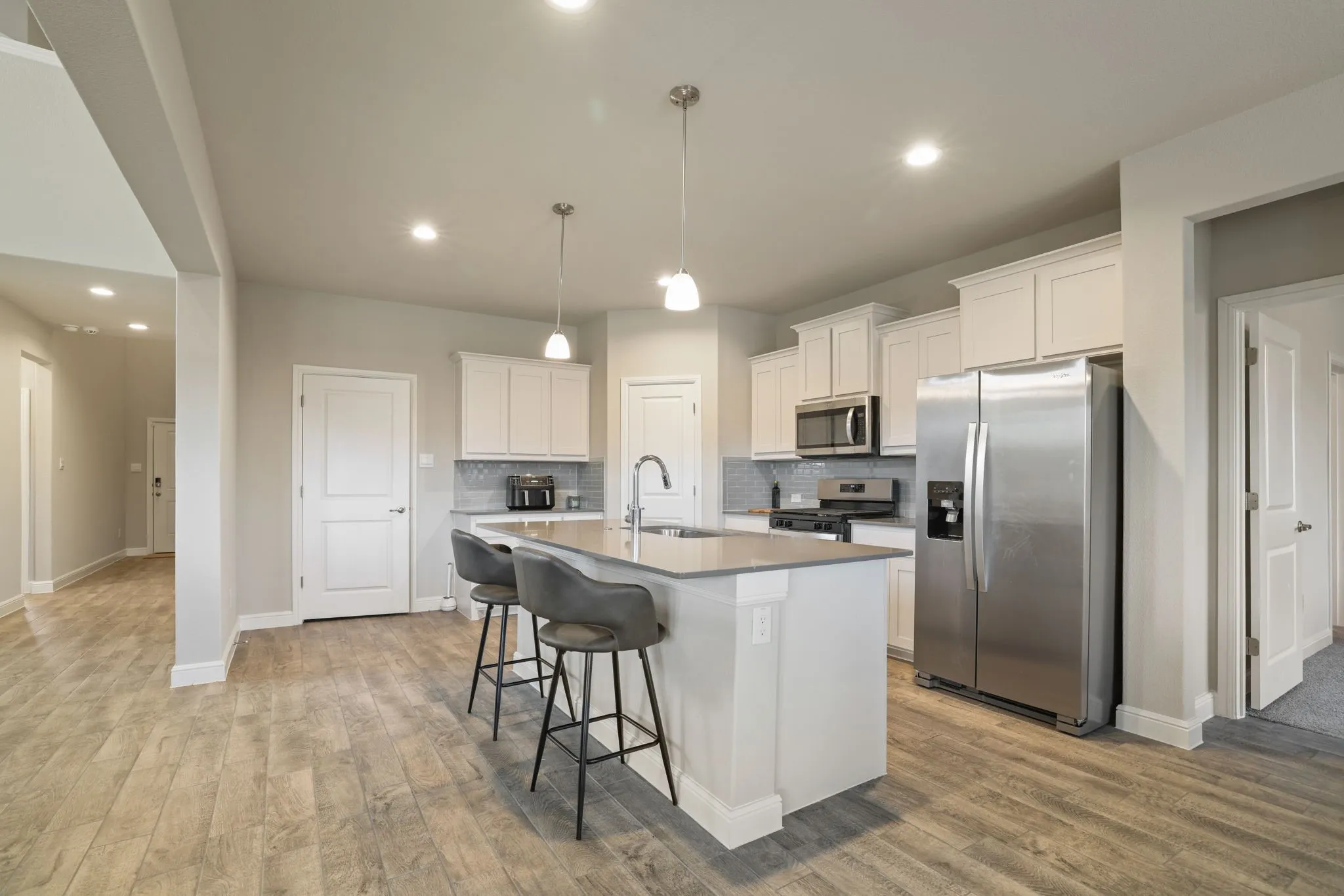 Kitchen featuring stainless steel appliances, white cabinets, a breakfast bar, decorative backsplash, and a kitchen island with sink